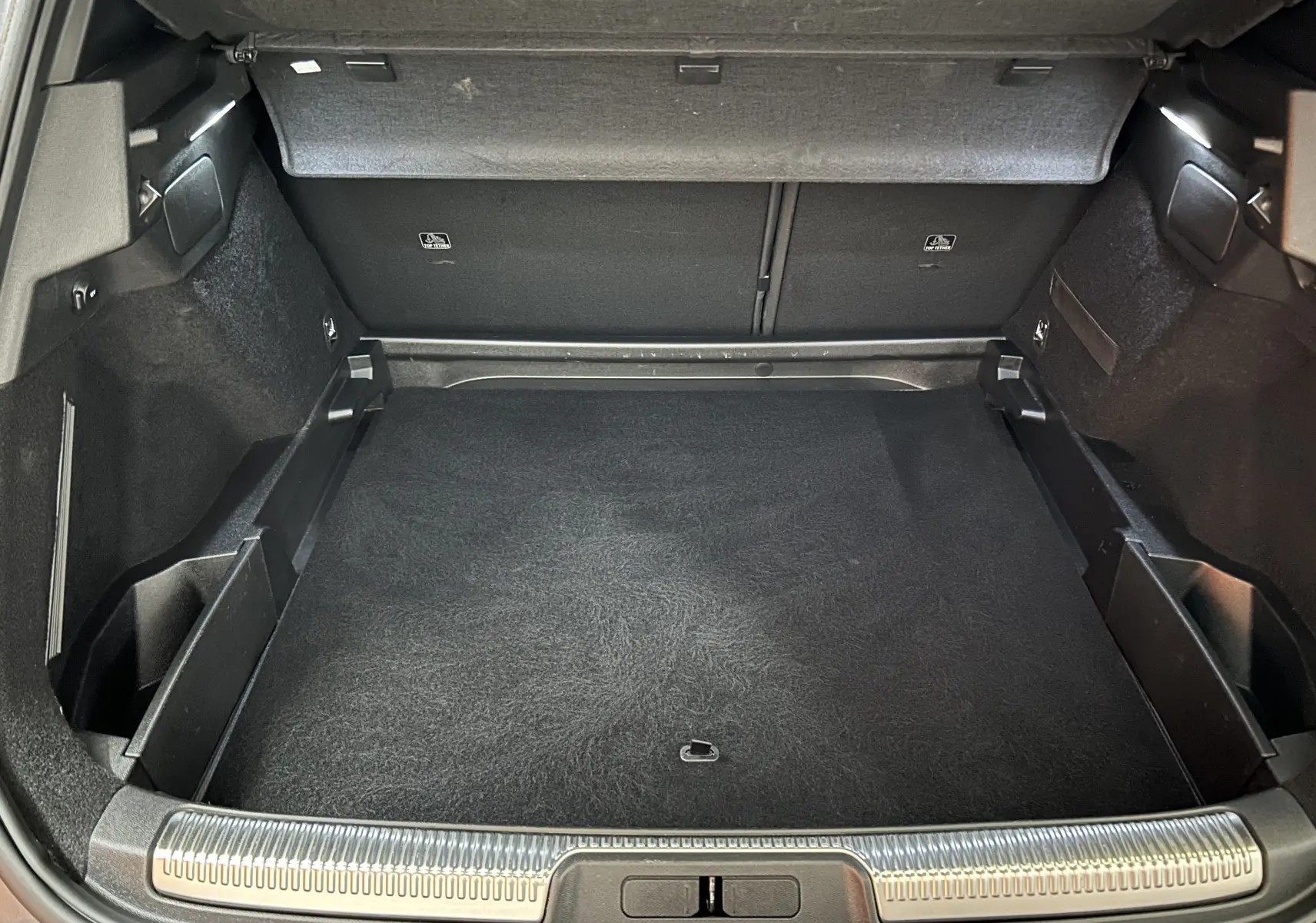 Coffre ouvert vu de l'arrière d'un DS7 gris titane, montrant un espace de chargement propre et bien aménagé.