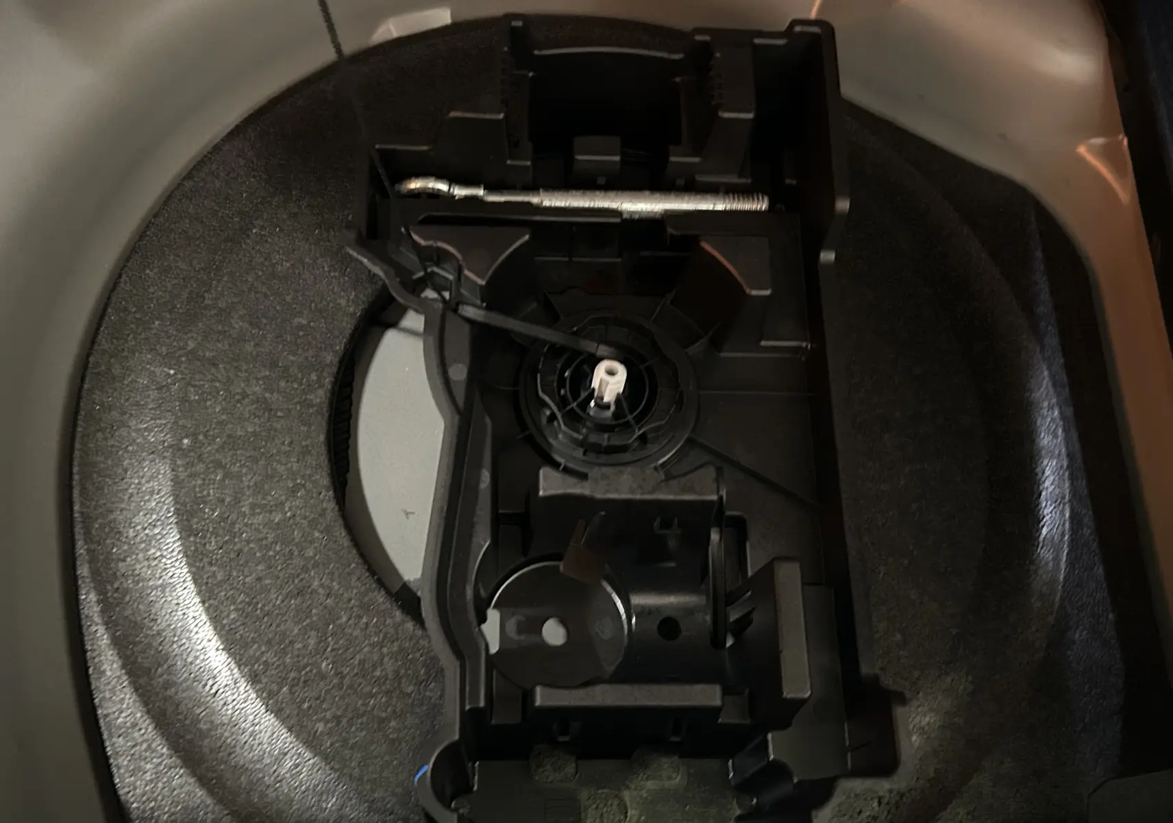 Gros plan sur le rangement de la roue de secours dans le coffre d’une DS7 gris titane, sans roue visible.