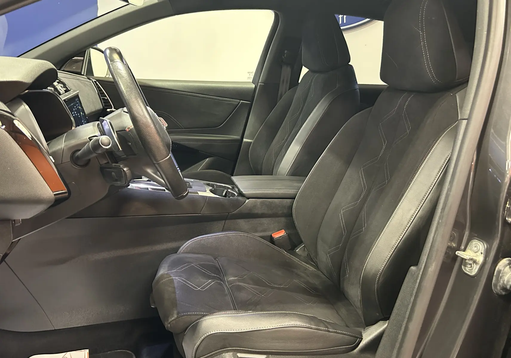 Vue intérieure côté conducteur du DS7 2024 gris titane, mettant en valeur les sièges en cuir Alcantara avec surpiqûres contrastées.