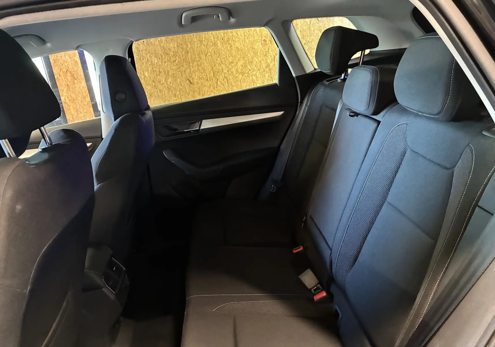 Vue intérieure côté droit des sièges arrière noirs du Skoda Karoq 2024 avec appuie-têtes et garnitures de porte sombres.