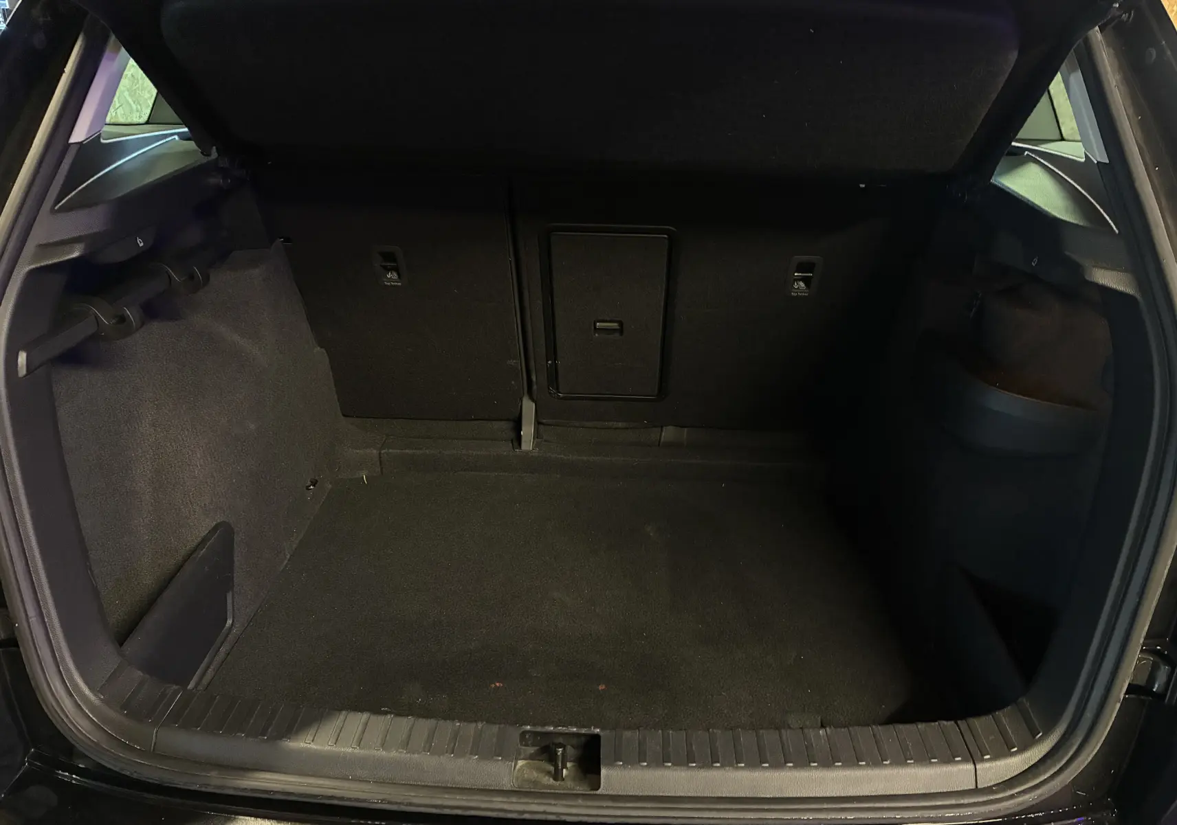 Coffre noir ouvert d'un Skoda Karoq 2024, montrant un espace de chargement propre avec trappe centrale arrière.