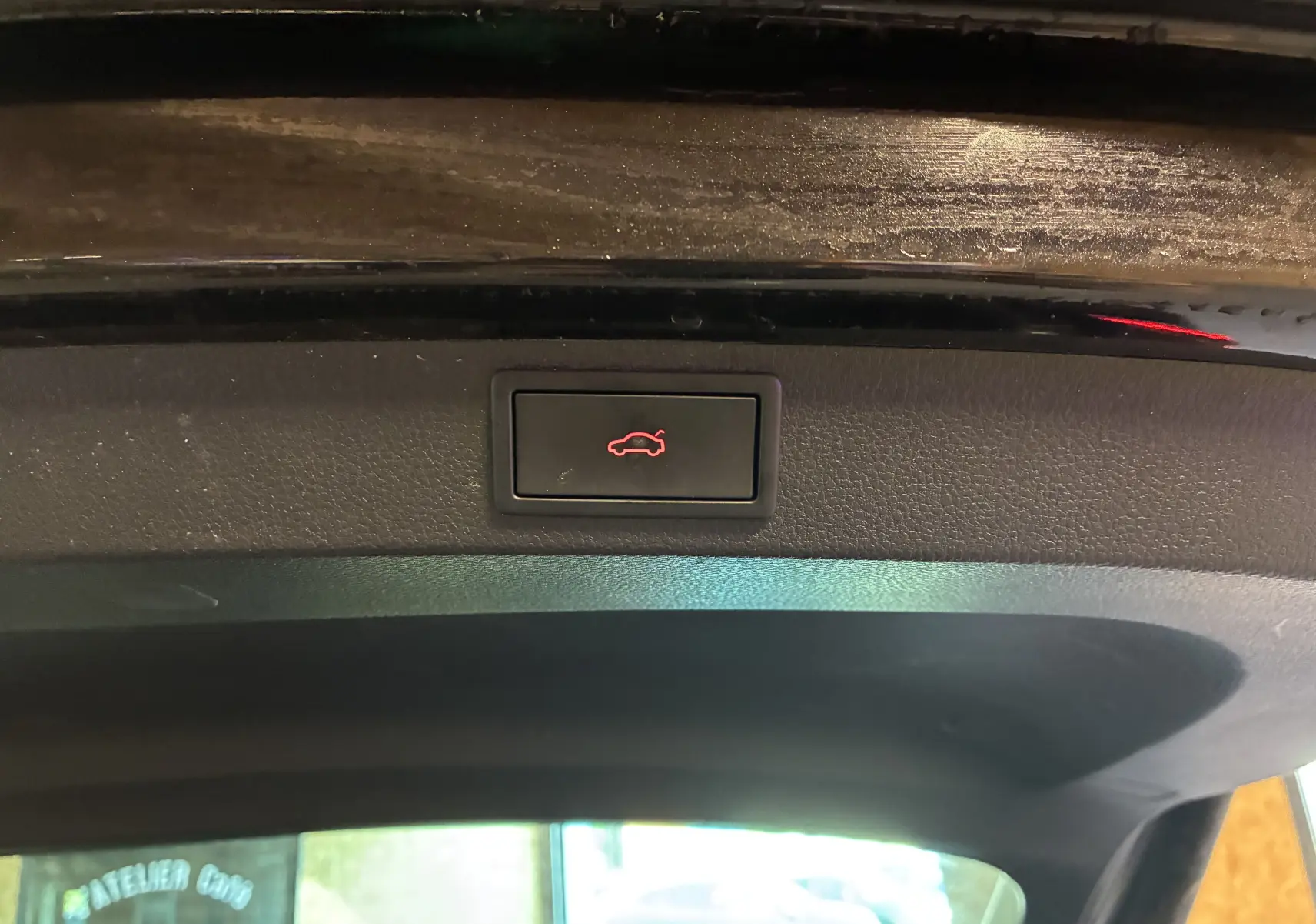Bouton d'ouverture électrique du coffre sur la garniture intérieure noire du hayon d'un Skoda Karoq noir.