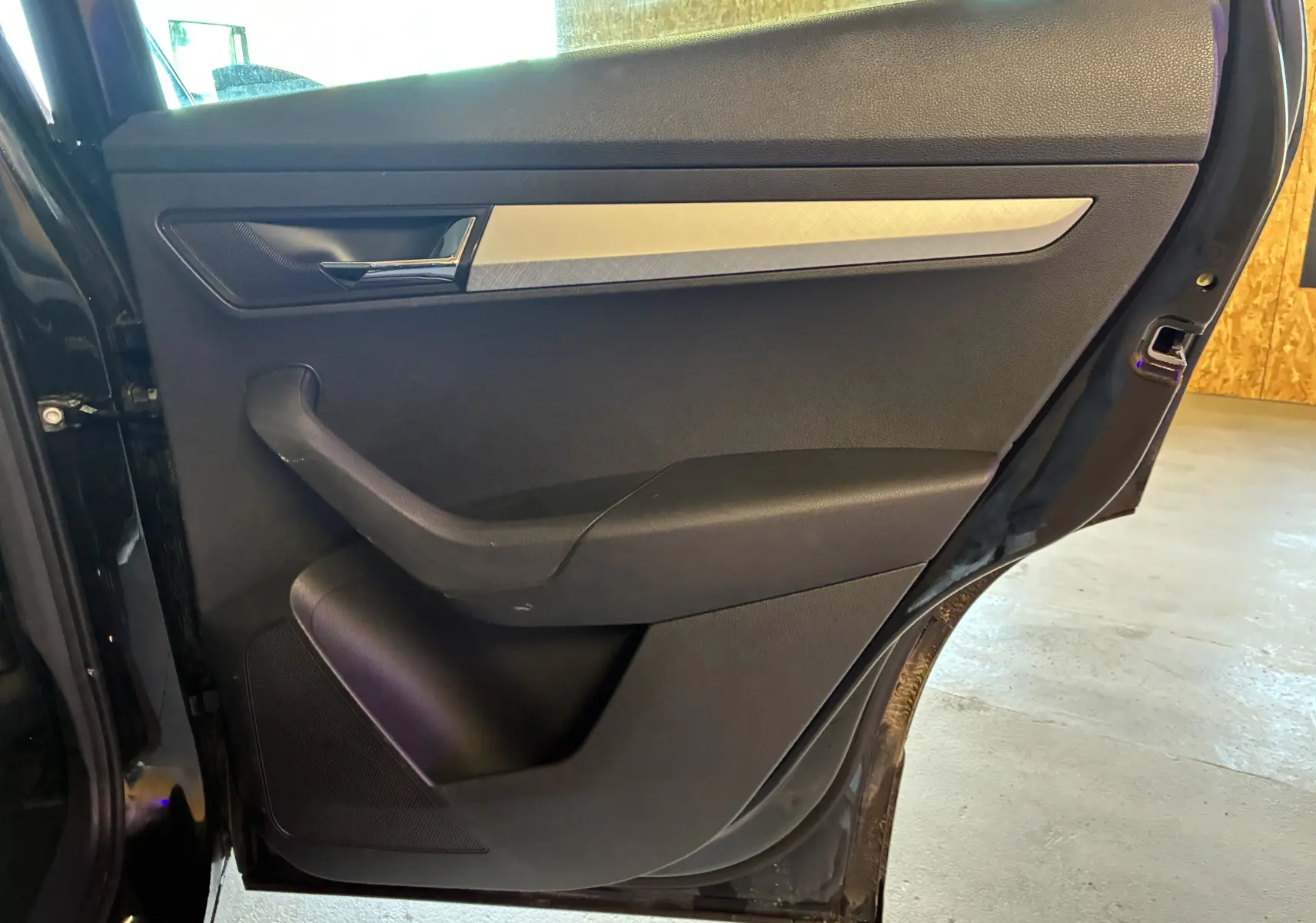 Vue intérieure de la porte arrière droite noire du Skoda Karoq 2024 avec poignée chromée et insert décoratif argenté.