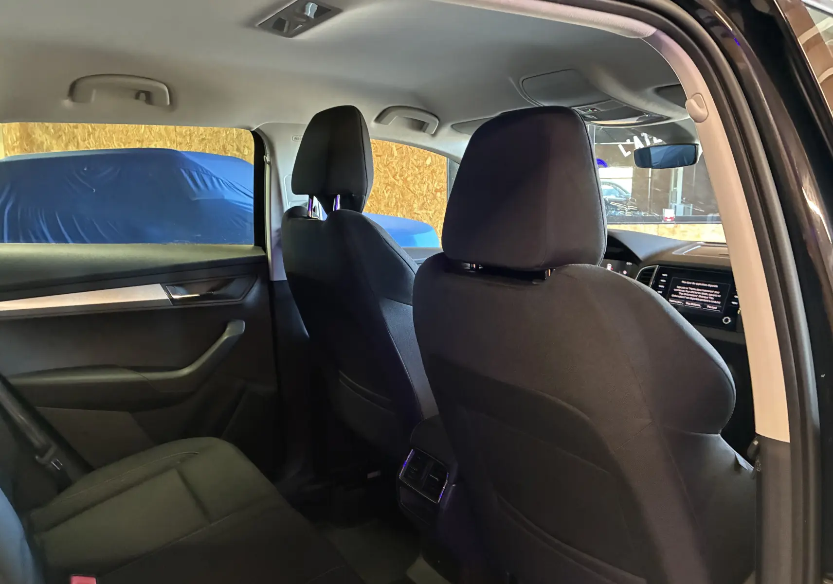 Intérieur arrière noir du Skoda Karoq 2024 vu côté gauche, avec sièges avant et aérateurs centraux visibles.