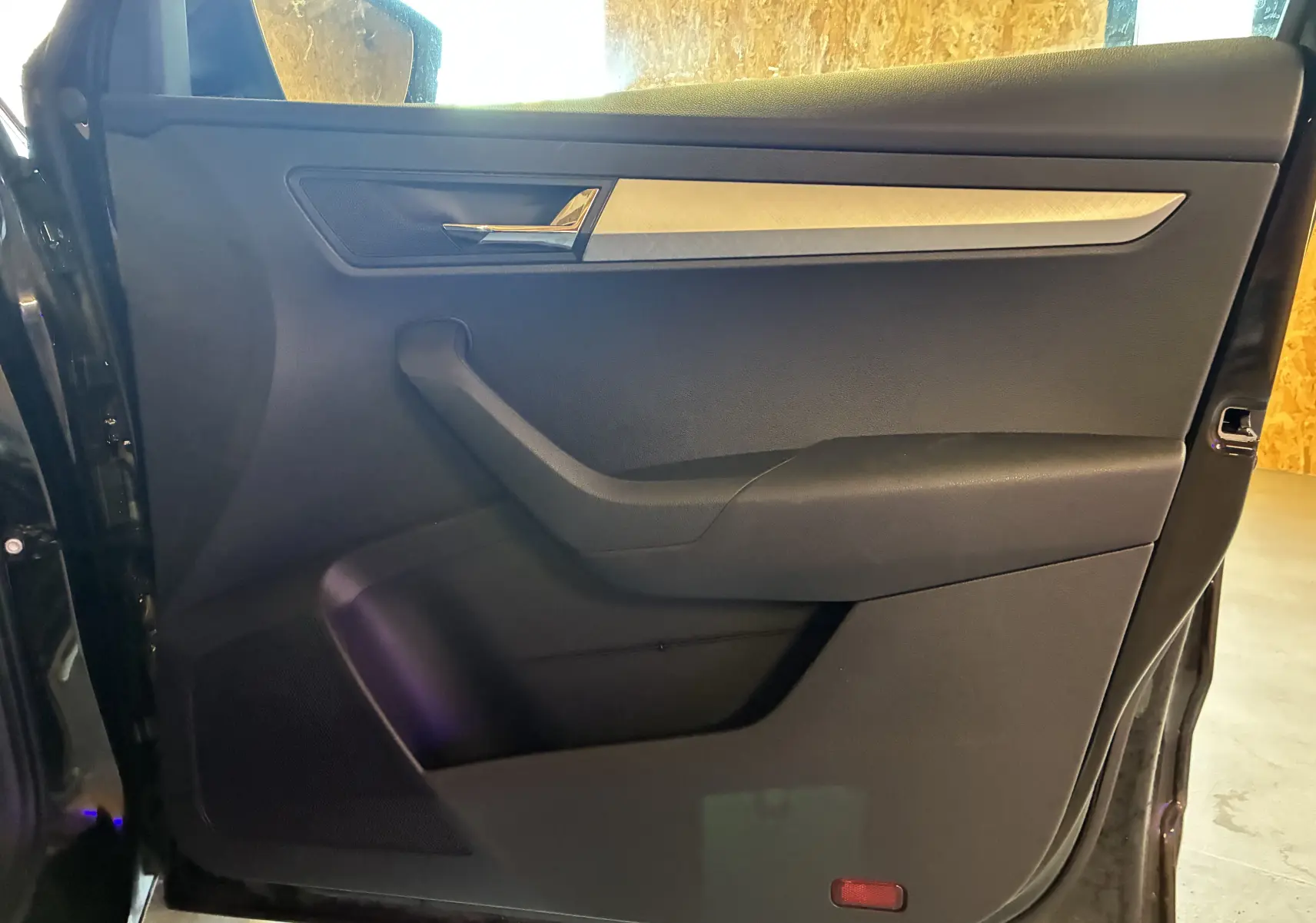 Vue intérieure de la porte arrière gauche noire du Skoda Karoq 2024 avec poignée chromée et insert argenté.