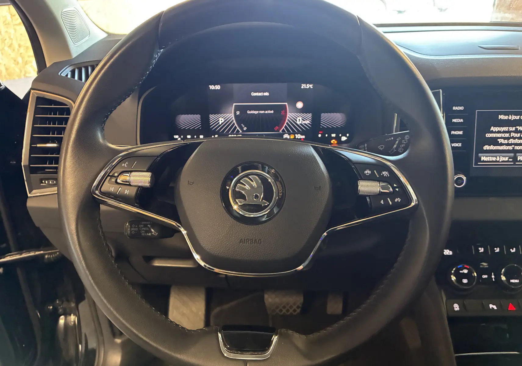 Vue rapprochée du volant multifonctions noir avec logo Škoda et tableau de bord digital du Karoq 2024.