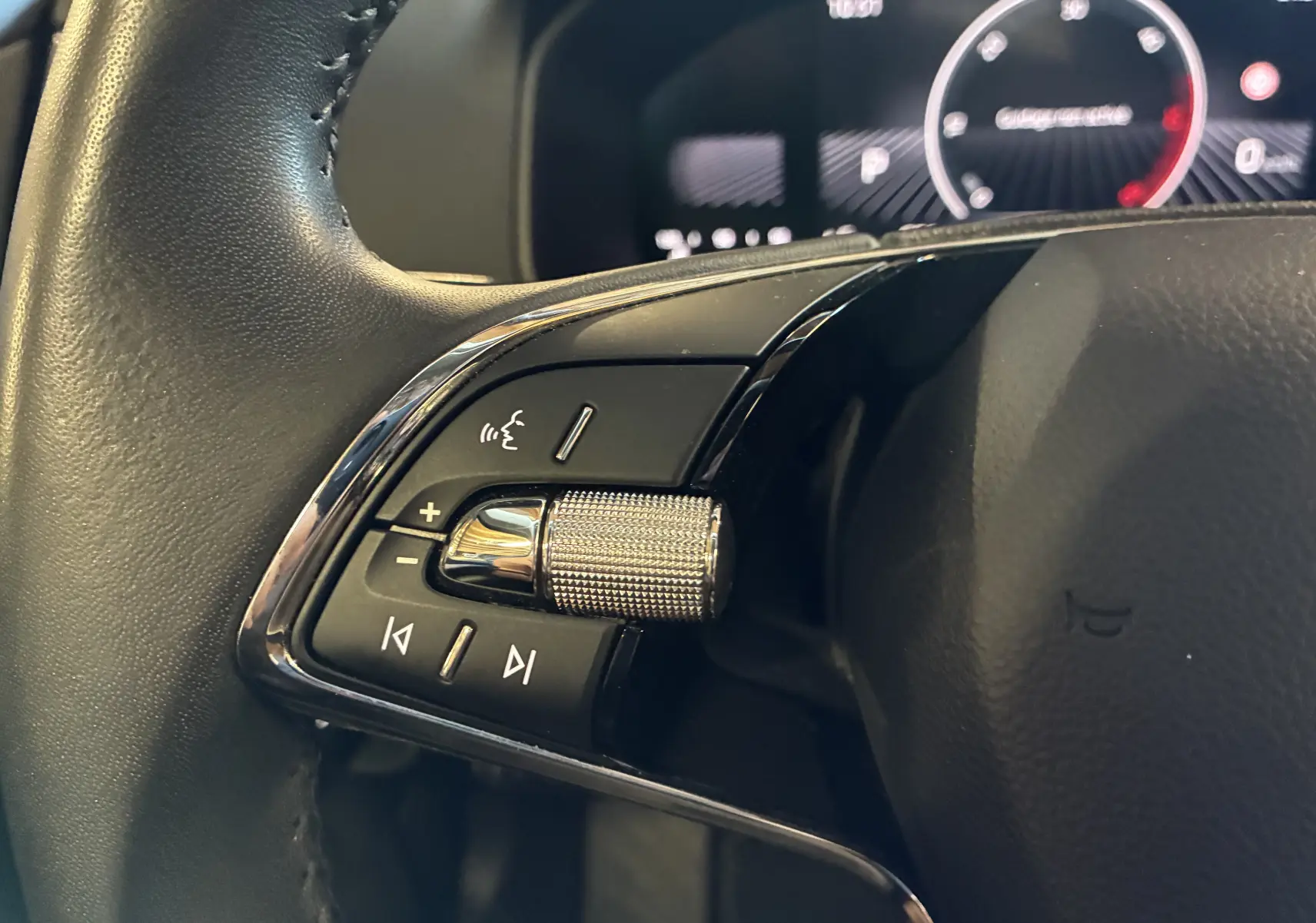 Gros plan sur la commande gauche du volant noir du Skoda Karoq 2024 avec molette chromée et boutons multifonctions.