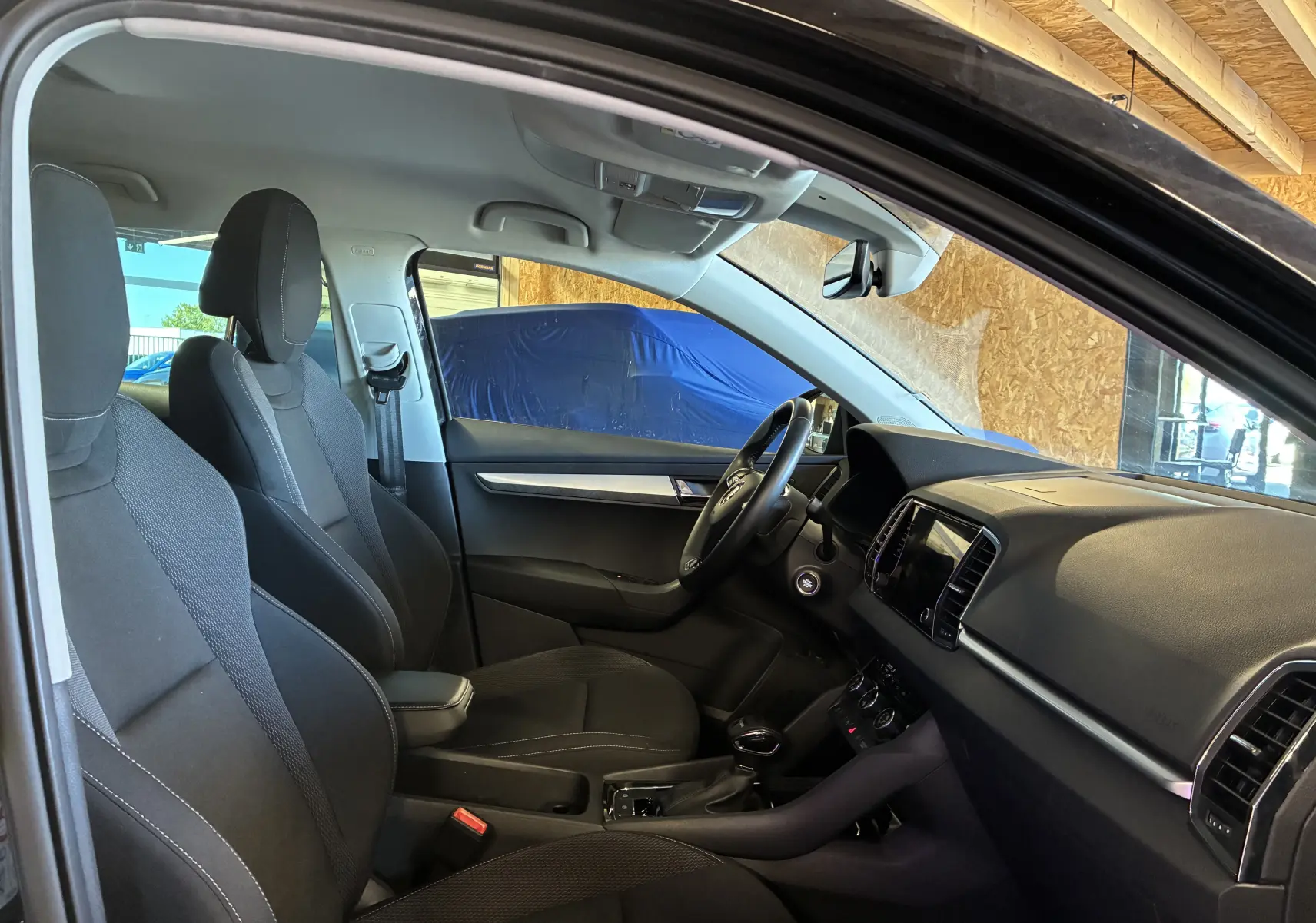 Intérieur noir de la Skoda Karoq 2024 vu côté conducteur, avec tableau de bord et sièges en tissu.