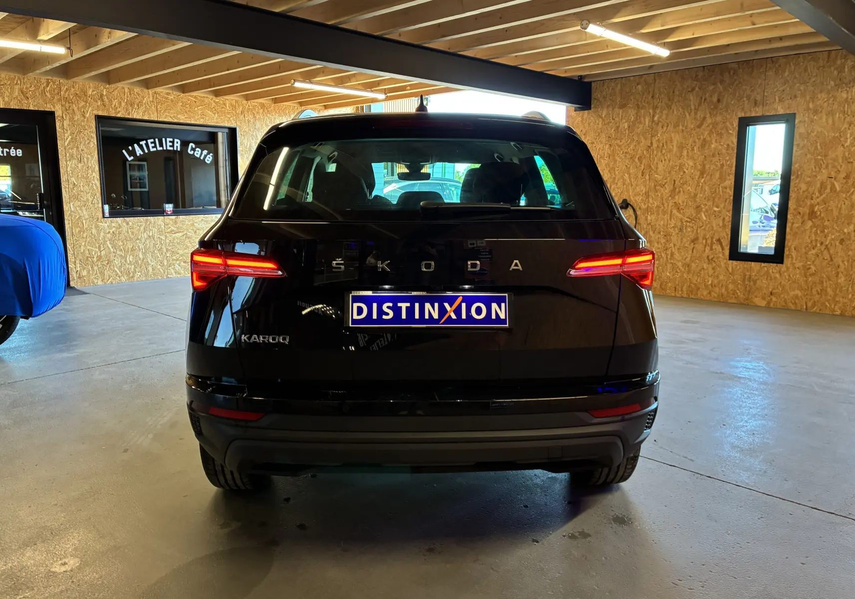 Vue arrière d'un Skoda Karoq noir 2024 avec feux LED allumés, dans un garage au sol béton.