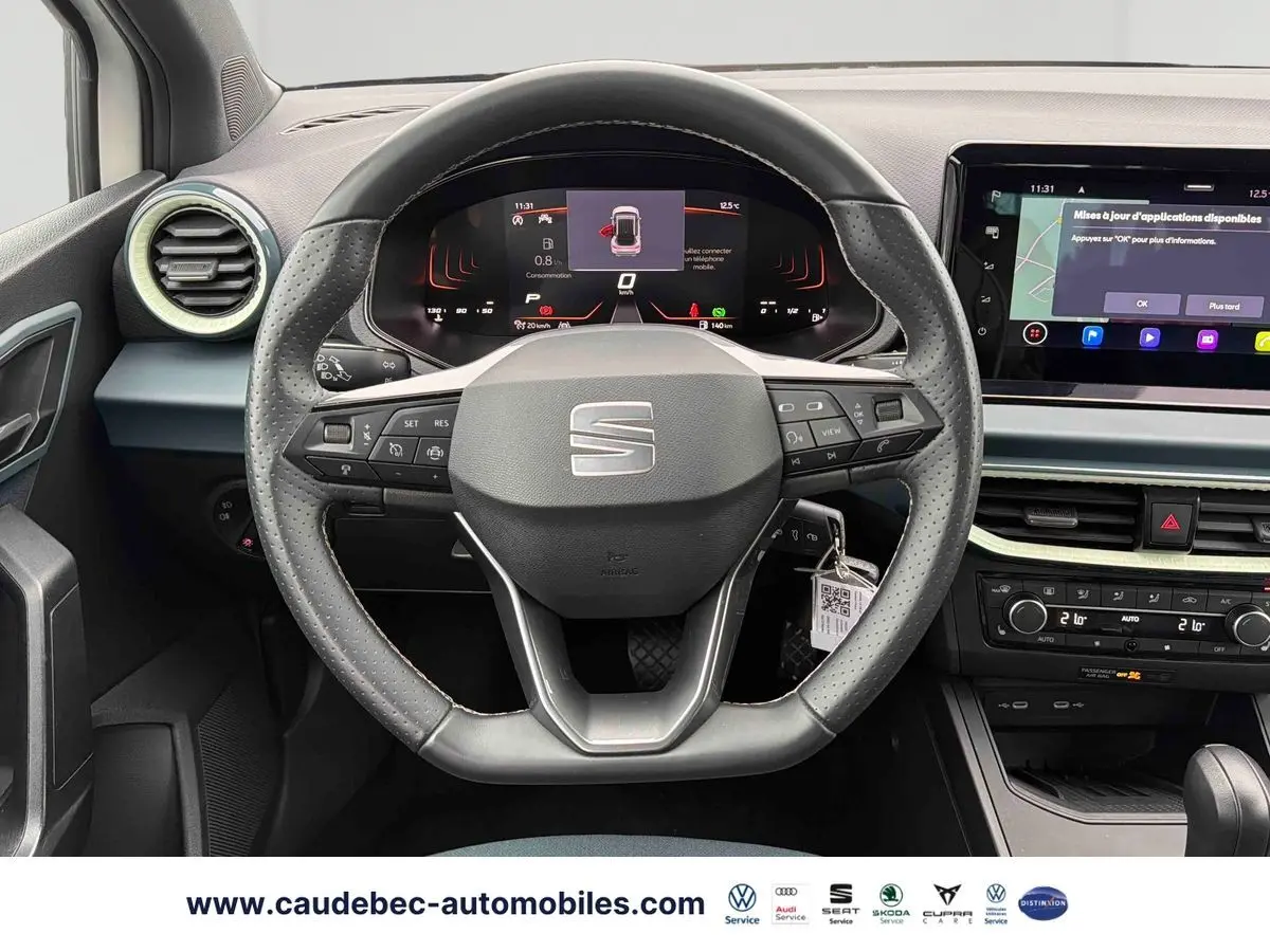 Vue intérieure centrée sur le volant cuir noir du SEAT Arona 2026 avec tableau de bord numérique et écran tactile.
