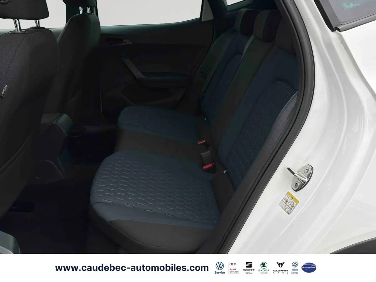 Vue intérieure côté arrière droit du SEAT Arona blanc, montrant les sièges arrière en tissu bleu et noir.