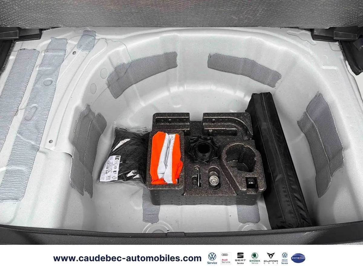Coffre ouvert du SEAT Arona blanc montrant le rangement sous plancher avec kit de secours et outils.