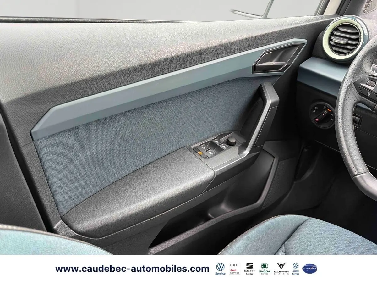 Vue intérieure côté conducteur du panneau de porte gris et noir du SEAT Arona 2026 avec commandes électriques des vitres.