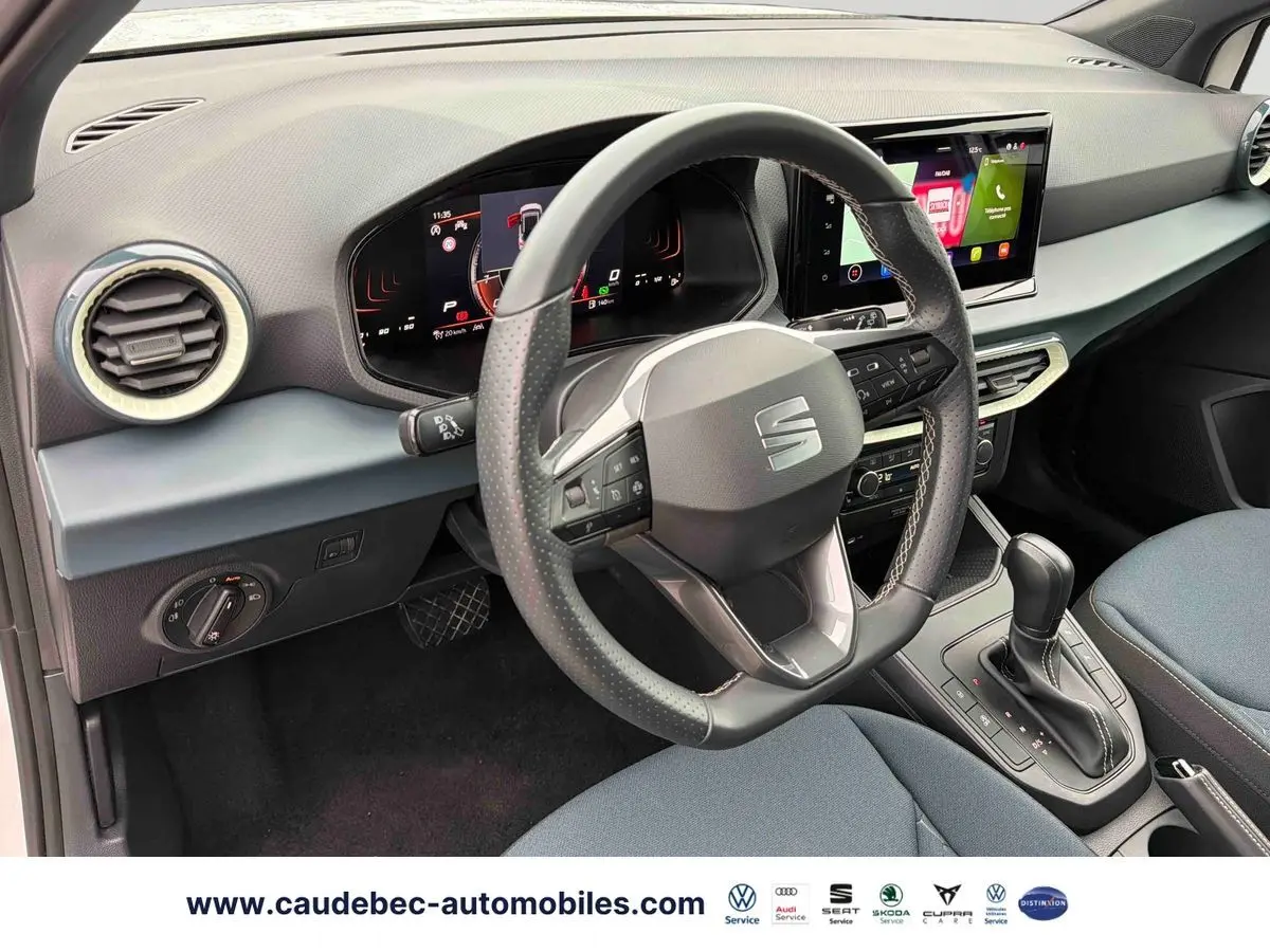 Vue intérieure côté conducteur du SEAT Arona blanc 2026, volant cuir multifonction et écran tactile central visible.