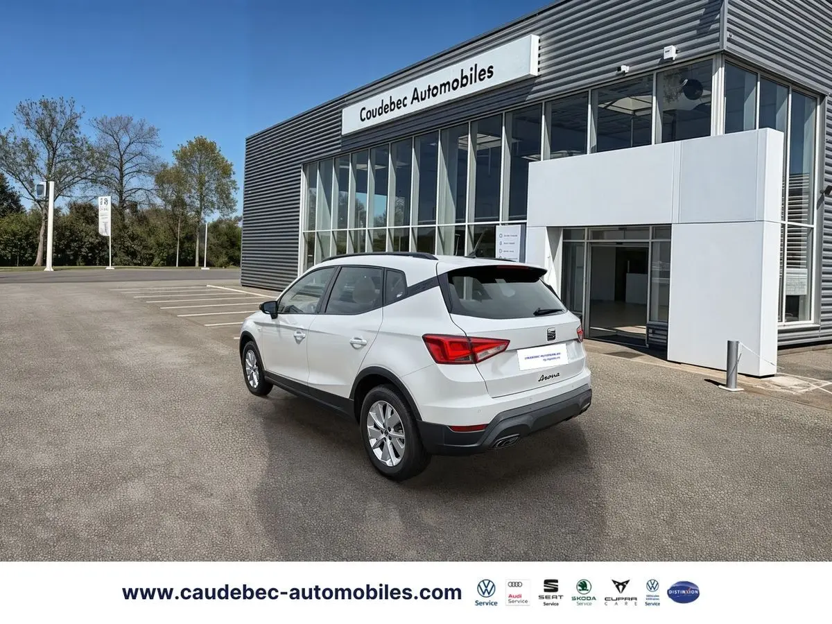 SEAT Arona blanche vue 3/4 arrière droit devant concession Coudebec Automobiles, jantes alliage 16 pouces.