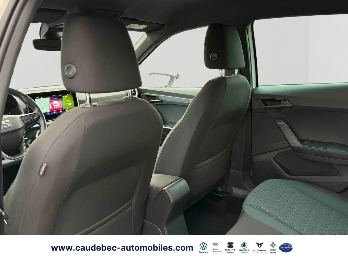 Intérieur arrière du SEAT Arona blanc, vue depuis la porte arrière gauche avec sièges noirs et tableau de bord digital visible.