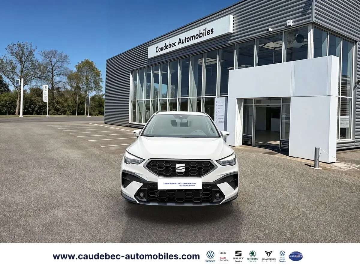 Vue avant d'un SEAT Arona blanc garé devant un bâtiment moderne de concession automobile.