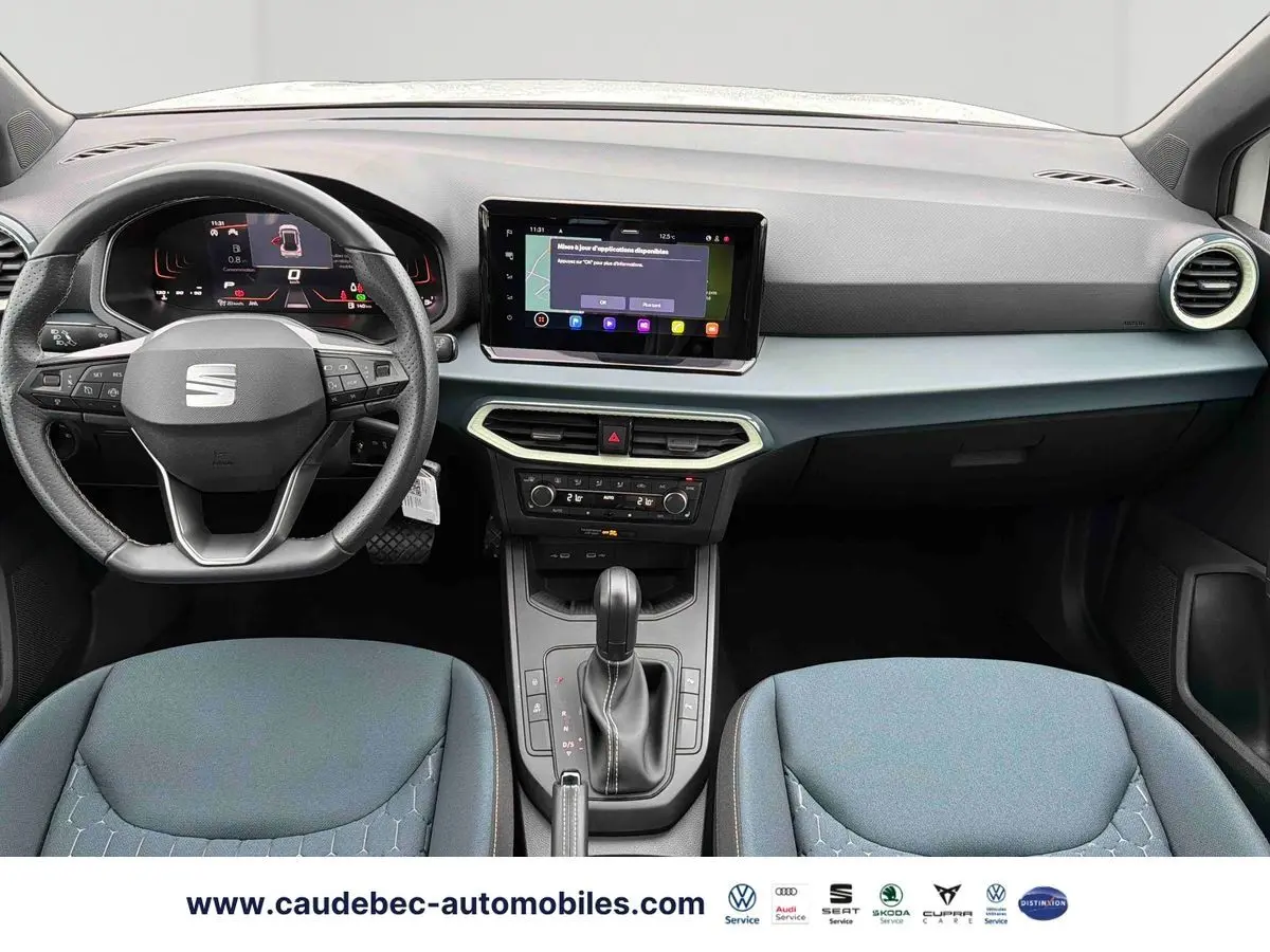 Vue intérieure avant du tableau de bord et volant noir de la SEAT Arona avec écran tactile central allumé.