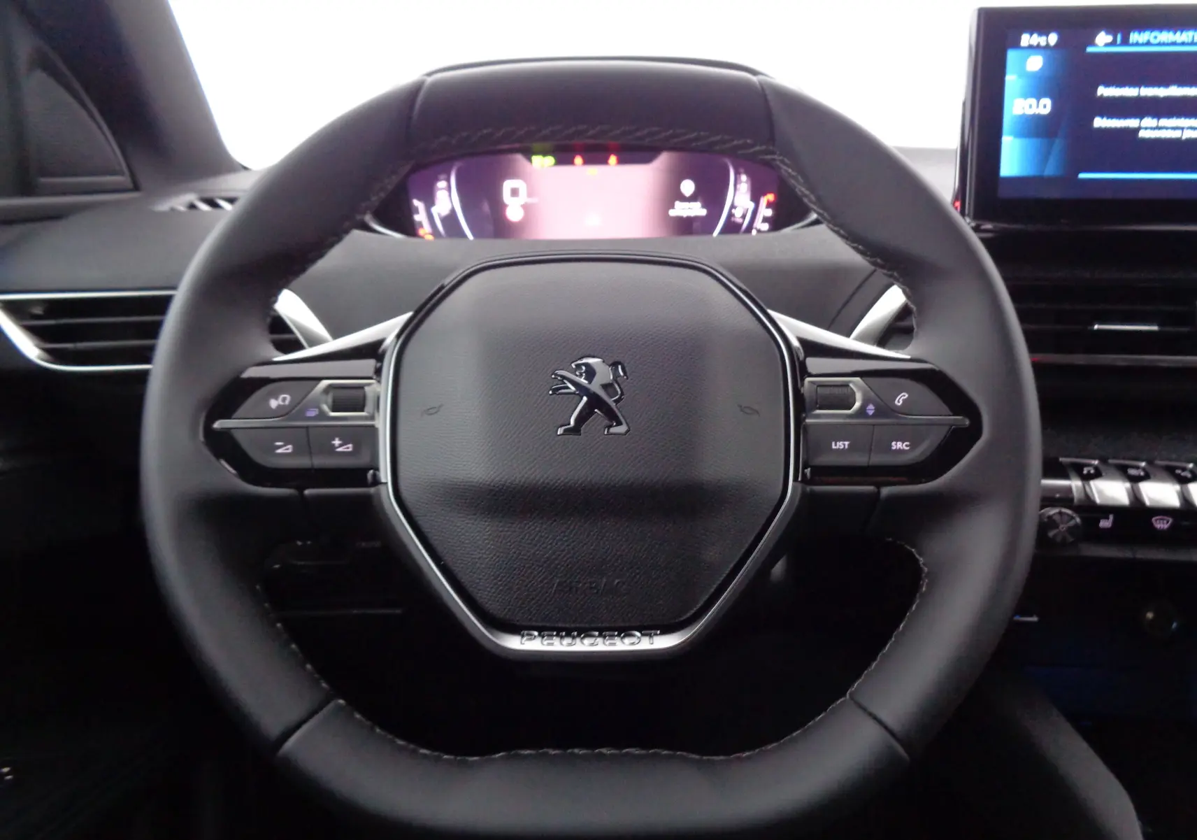 Volant cuir noir de Peugeot 3008 2023 avec commandes intégrées et tableau de bord numérique en arrière-plan.