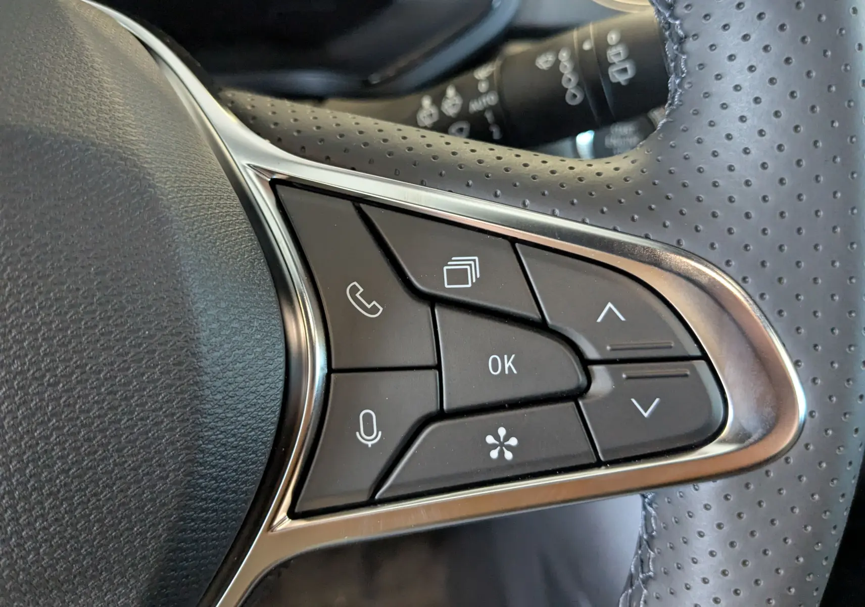 Gros plan sur les commandes multifonctions à droite du volant perforé d’un Renault Captur E-Tech hybride 2025.