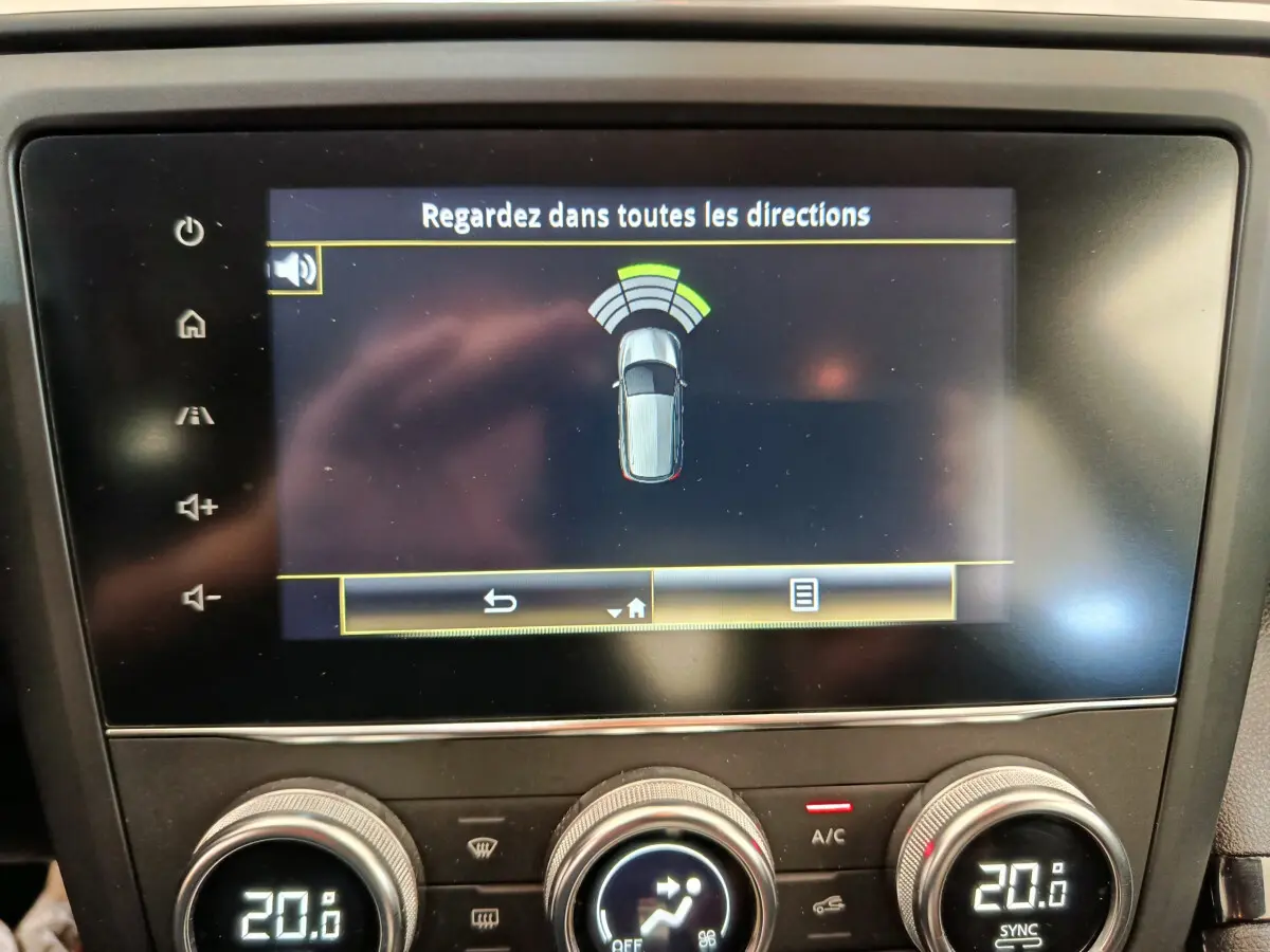 Écran tactile central affichant l'aide au stationnement avec vue aérienne du Renault Kadjar gris foncé, tableau de bord visible.