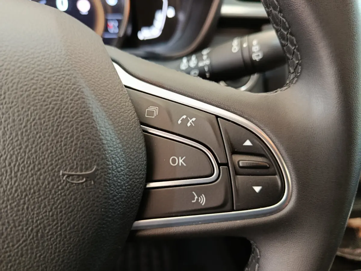 Gros plan sur les commandes multifonctions du volant noir du Renault Kadjar Business 2022, avec boutons OK et téléphone.