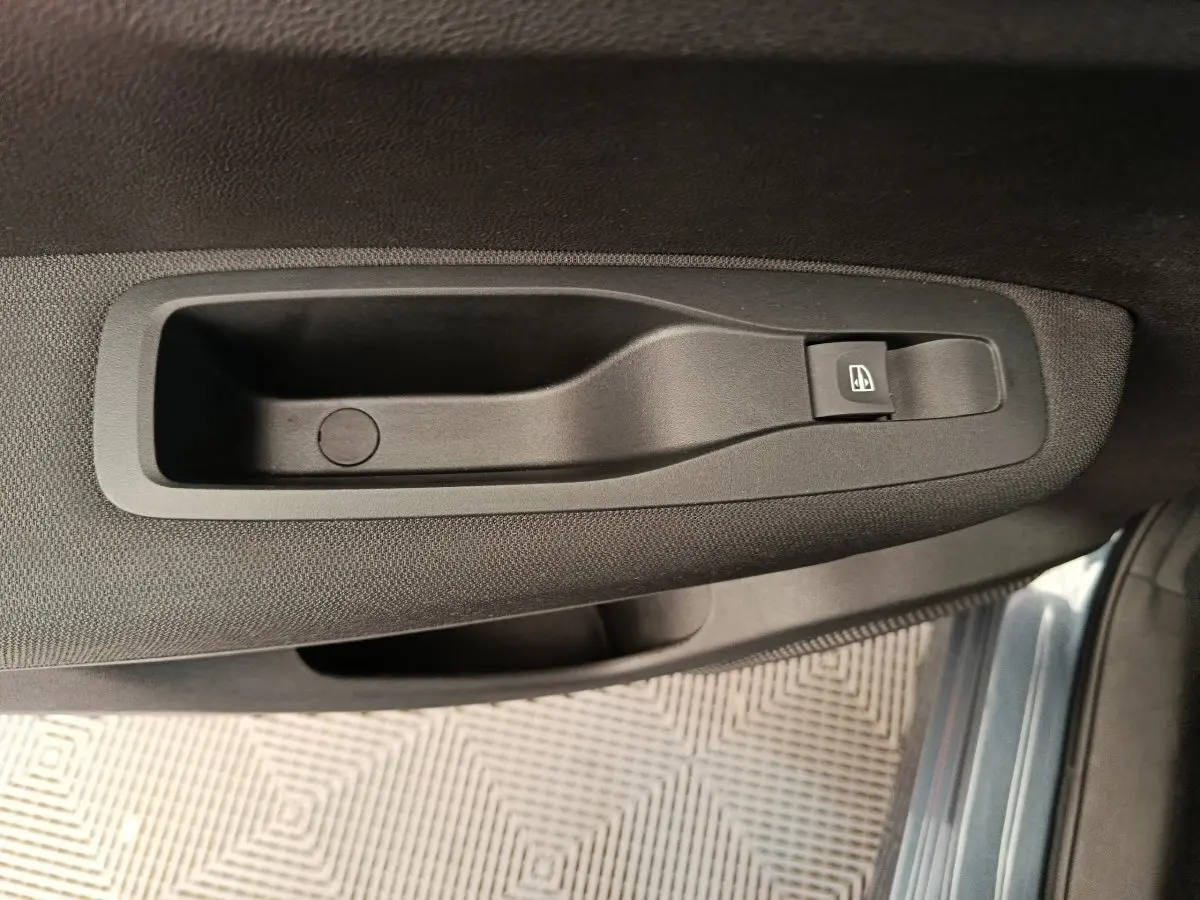 Poignée intérieure côté gauche avec bouton de commande de vitre sur porte d'un Renault Kadjar gris foncé 2022.