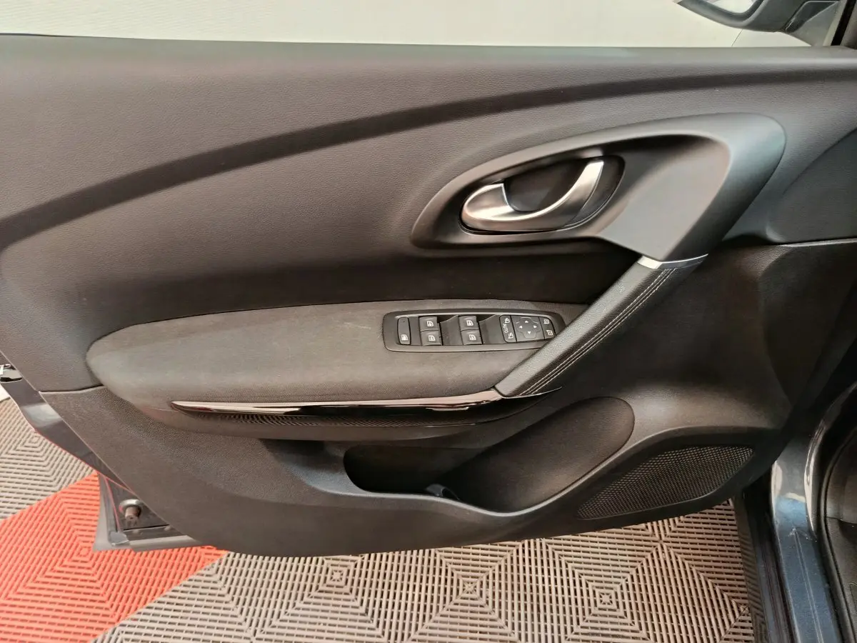 Gros plan sur la porte côté conducteur du Renault Kadjar gris foncé, avec commandes électriques et poignée argentée.