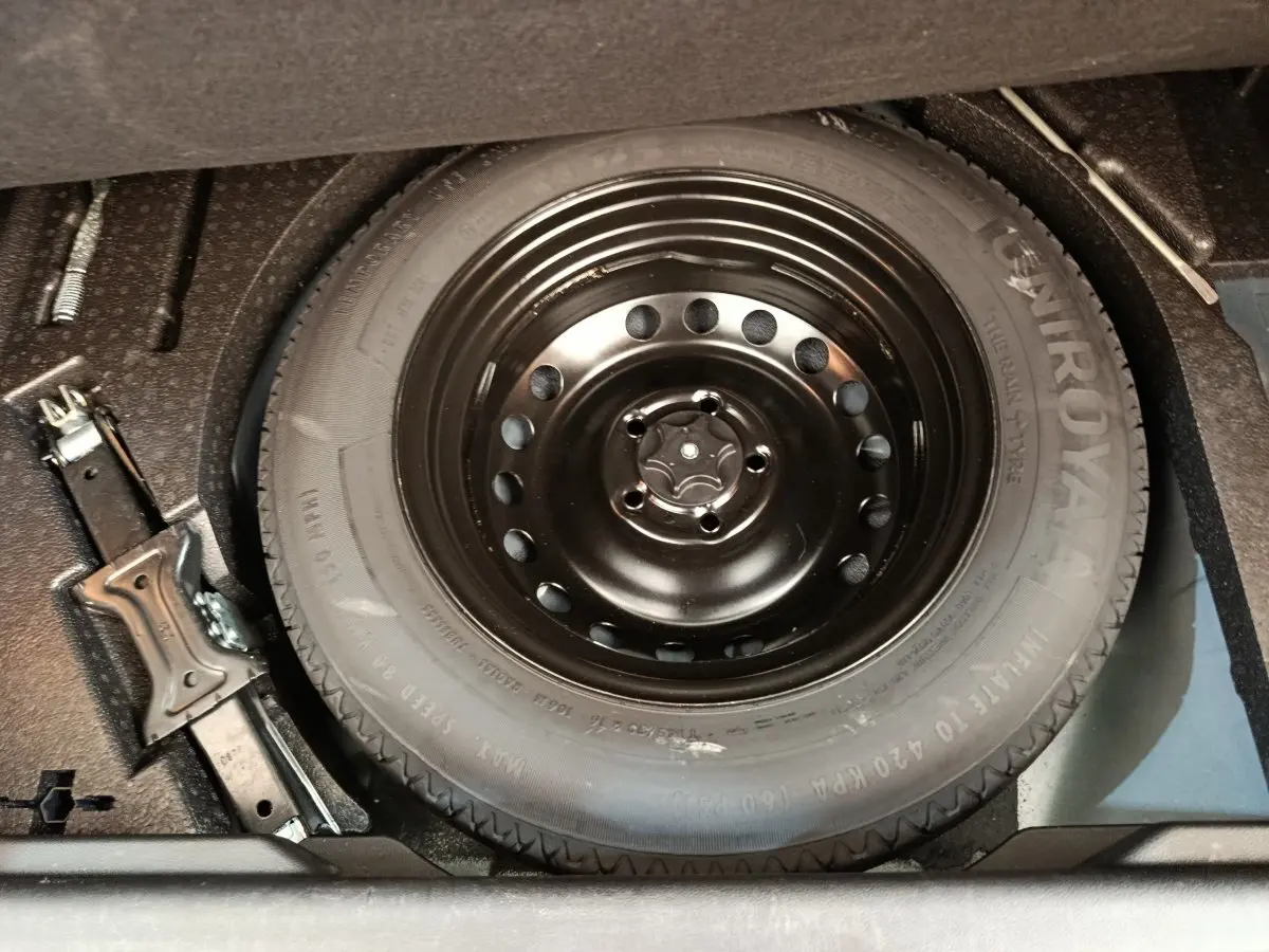 Gros plan sur la roue de secours noire et le cric dans le coffre d’un Renault Kadjar gris foncé 2022.