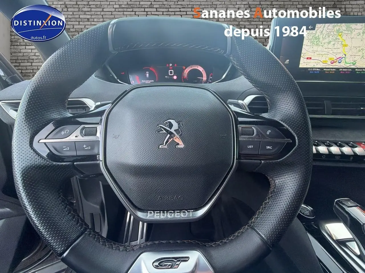 Vue rapprochée du volant cuir perforé avec badge GT et tableau de bord numérique du Peugeot 3008 gris foncé.