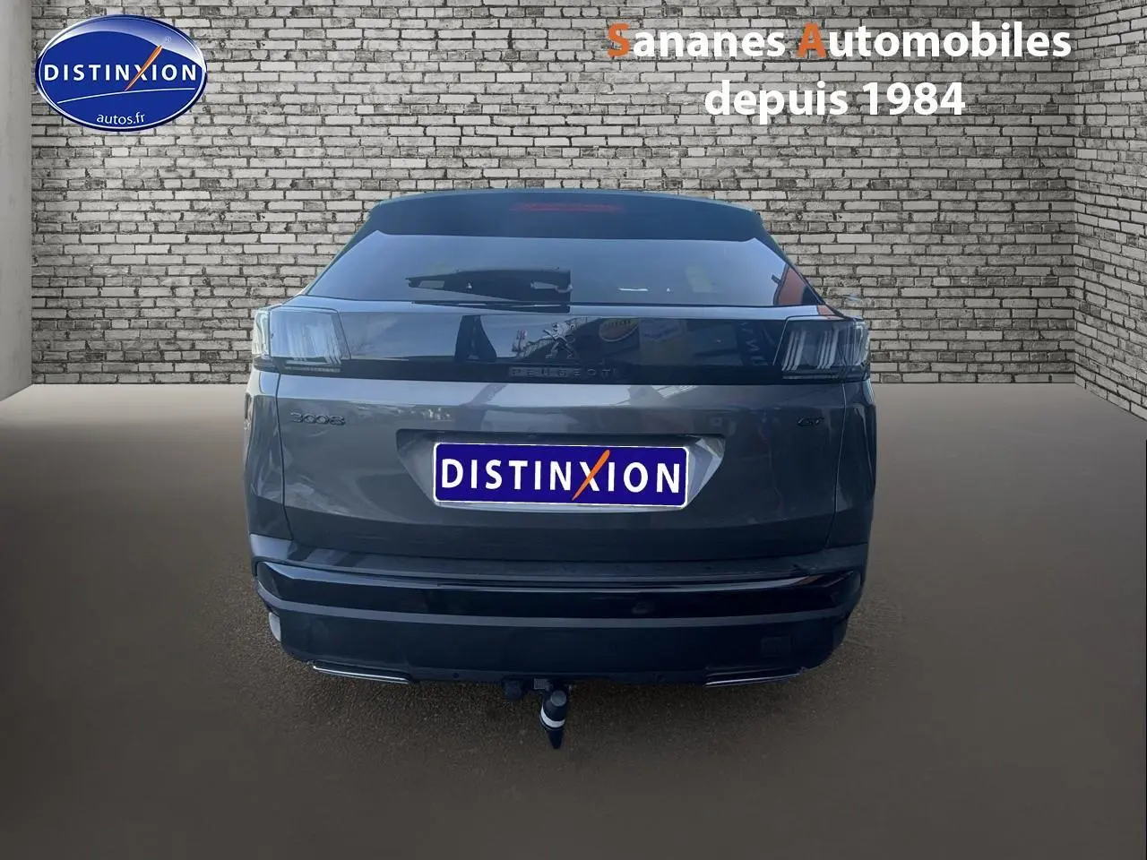 Vue arrière d’un Peugeot 3008 gris foncé avec attelage et bandeau noir brillant sur pare-chocs arrière.
