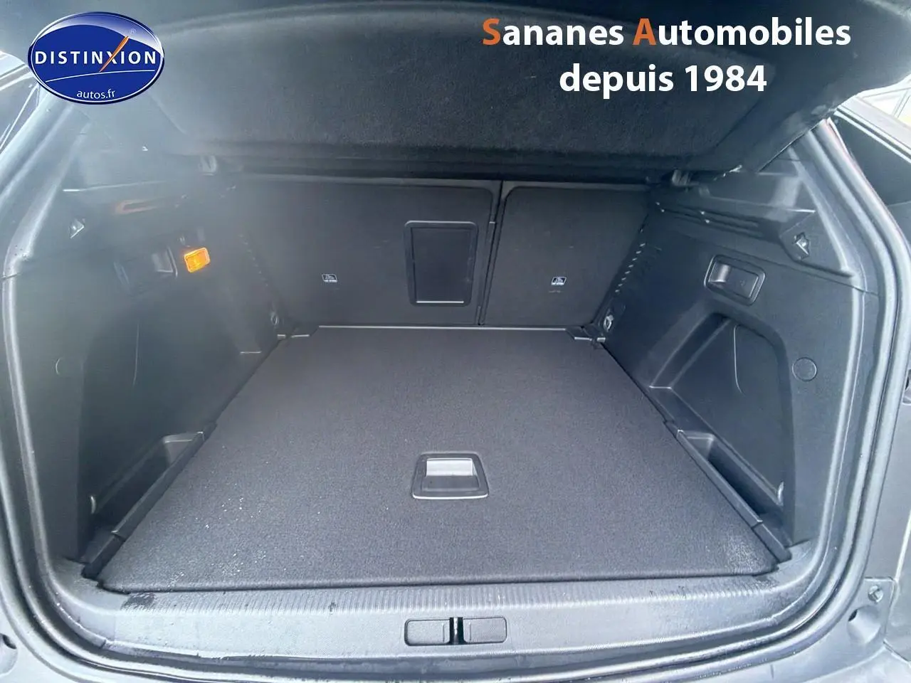Coffre ouvert vu de l'arrière d'un Peugeot 3008 gris foncé avec intérieur noir et banquette rabattable.