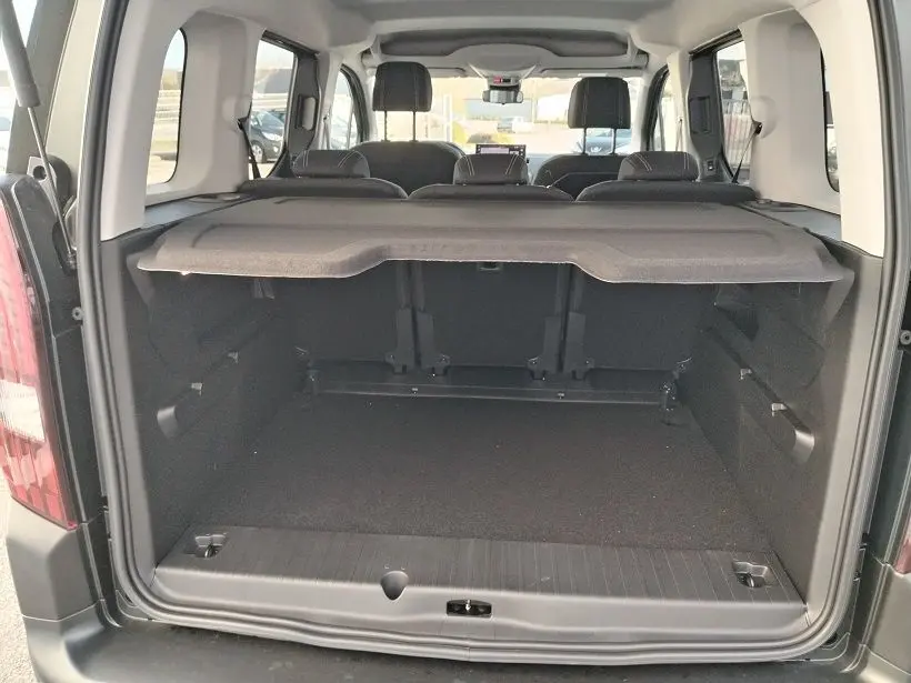 Vue arrière ouverte du coffre spacieux du Peugeot Rifter 2025 en Srikka Green, avec banquette arrière et cache-bagages visibles.