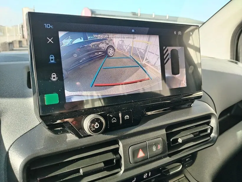 Vue intérieure du tableau de bord du Peugeot Rifter 2025, écran tactile affichant la caméra de recul avec lignes de guidage.
