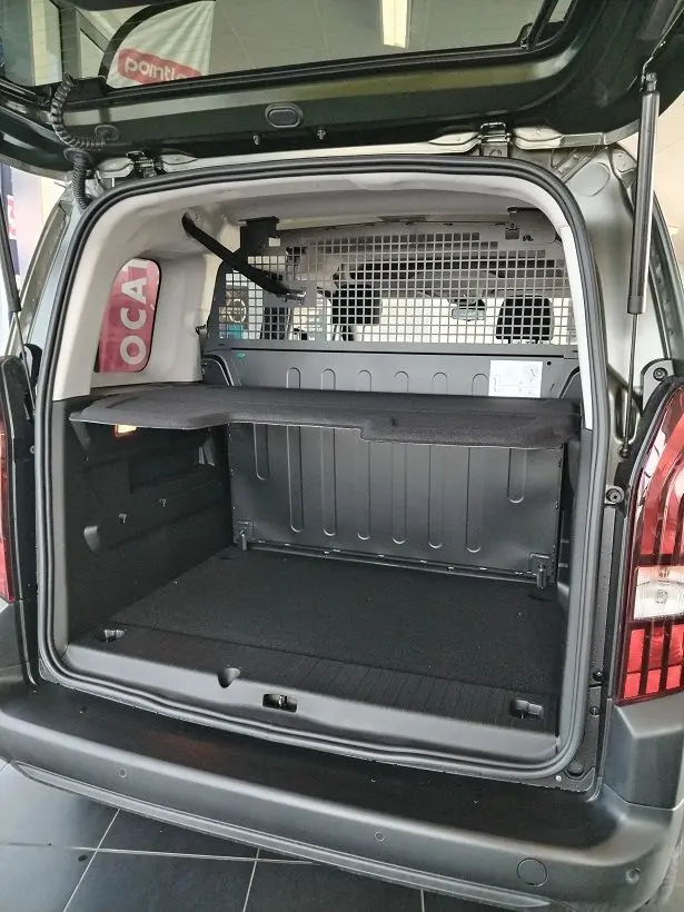 Vue arrière ouverte du Peugeot Rifter 2025 vert Srikka, montrant le coffre spacieux avec séparation grillagée.