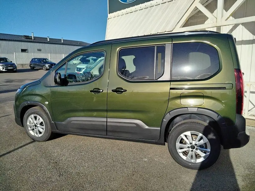 Vue de profil côté gauche d'un Peugeot Rifter 2025 vert Srikka avec roues alliage et protections noires.