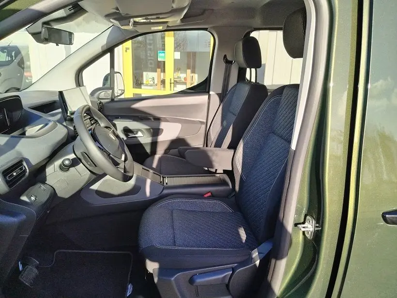 Vue intérieure côté gauche du Peugeot Rifter 2025 vert Srikka, montrant les sièges avant en tissu et le tableau de bord moderne.