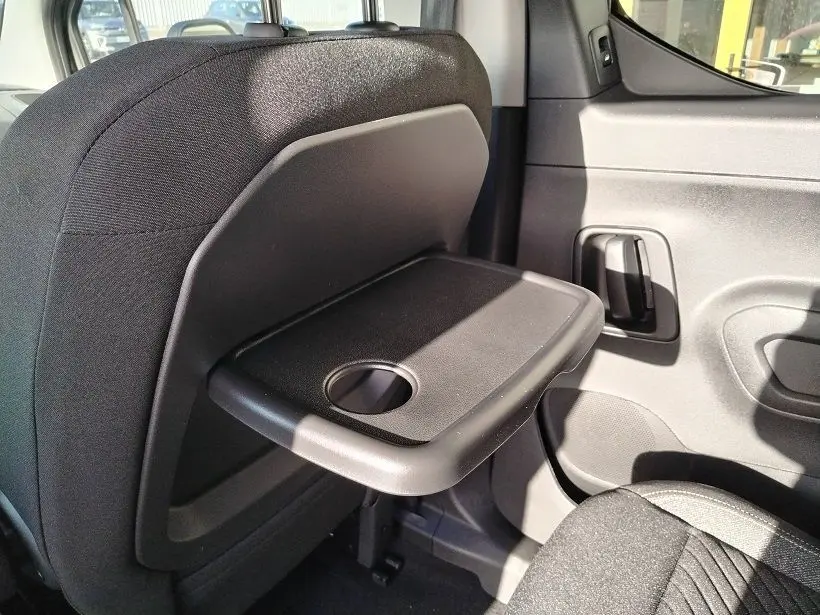 Détail intérieur côté droit du Peugeot Rifter 2025, tablette pliable noire fixée au dossier du siège avant.