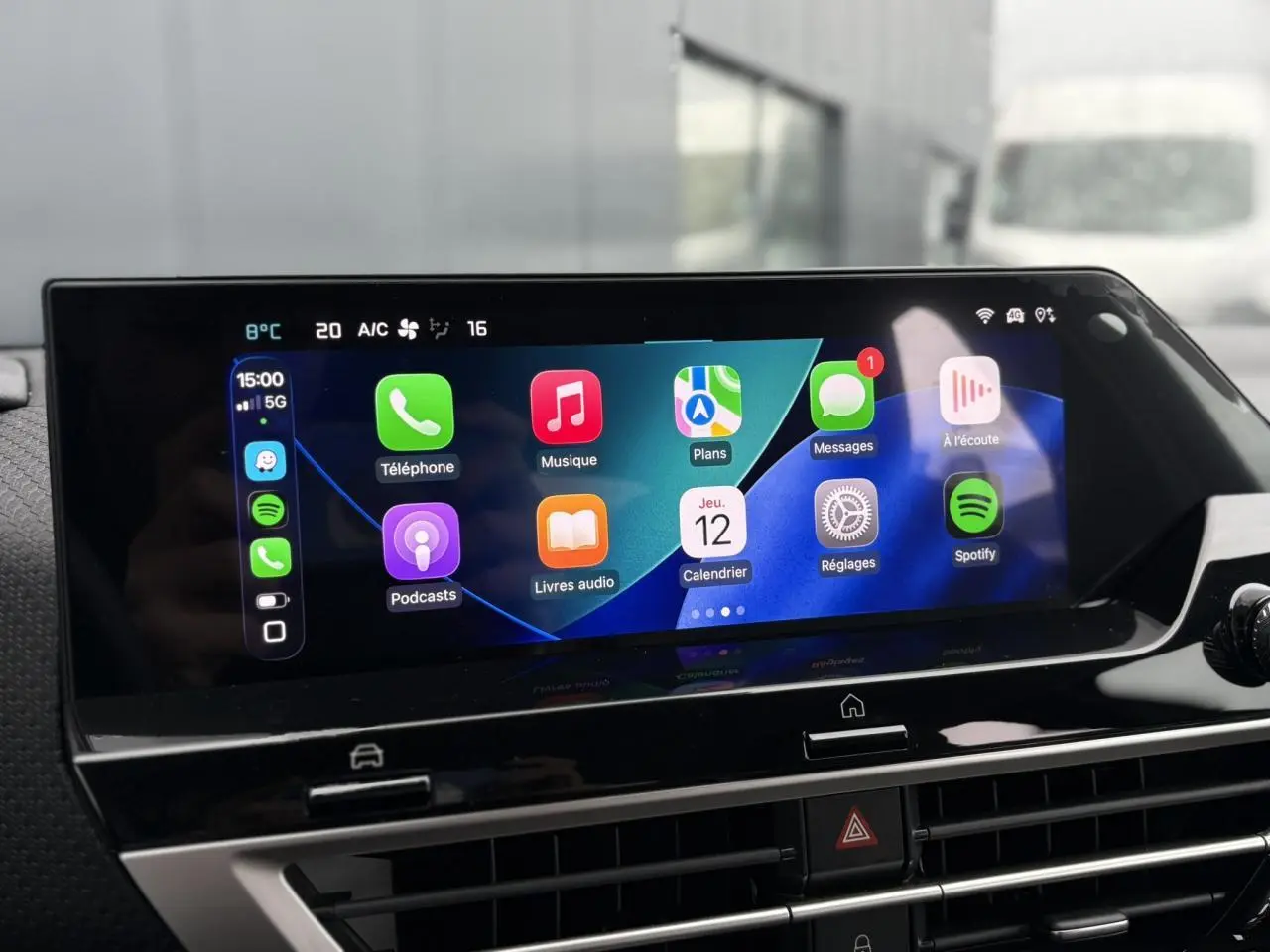 Écran tactile central de la Citroën C4 Hybrid 2025 affichant Apple CarPlay avec icônes colorées, vue intérieure frontale.