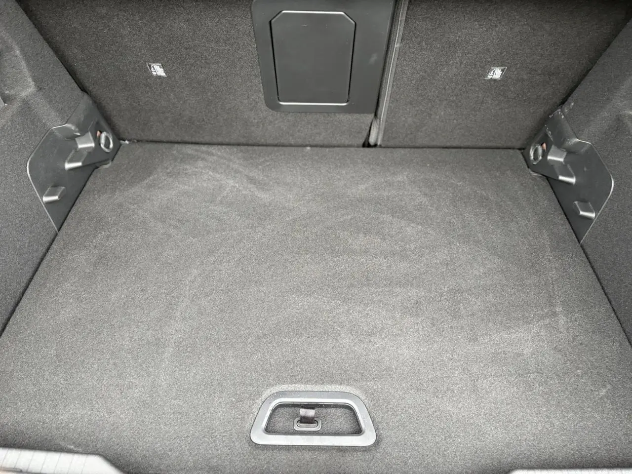 Vue plongeante sur le coffre spacieux et tapissé de tissu noir du Citroën C4 Hybrid 2025.