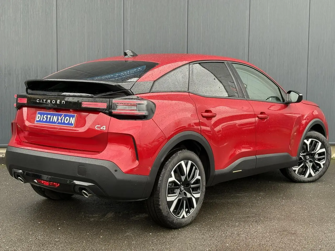 Vue 3/4 arrière droite d'une Citroën C4 rouge Elixir avec jantes alliage et feux arrière LED distinctifs.