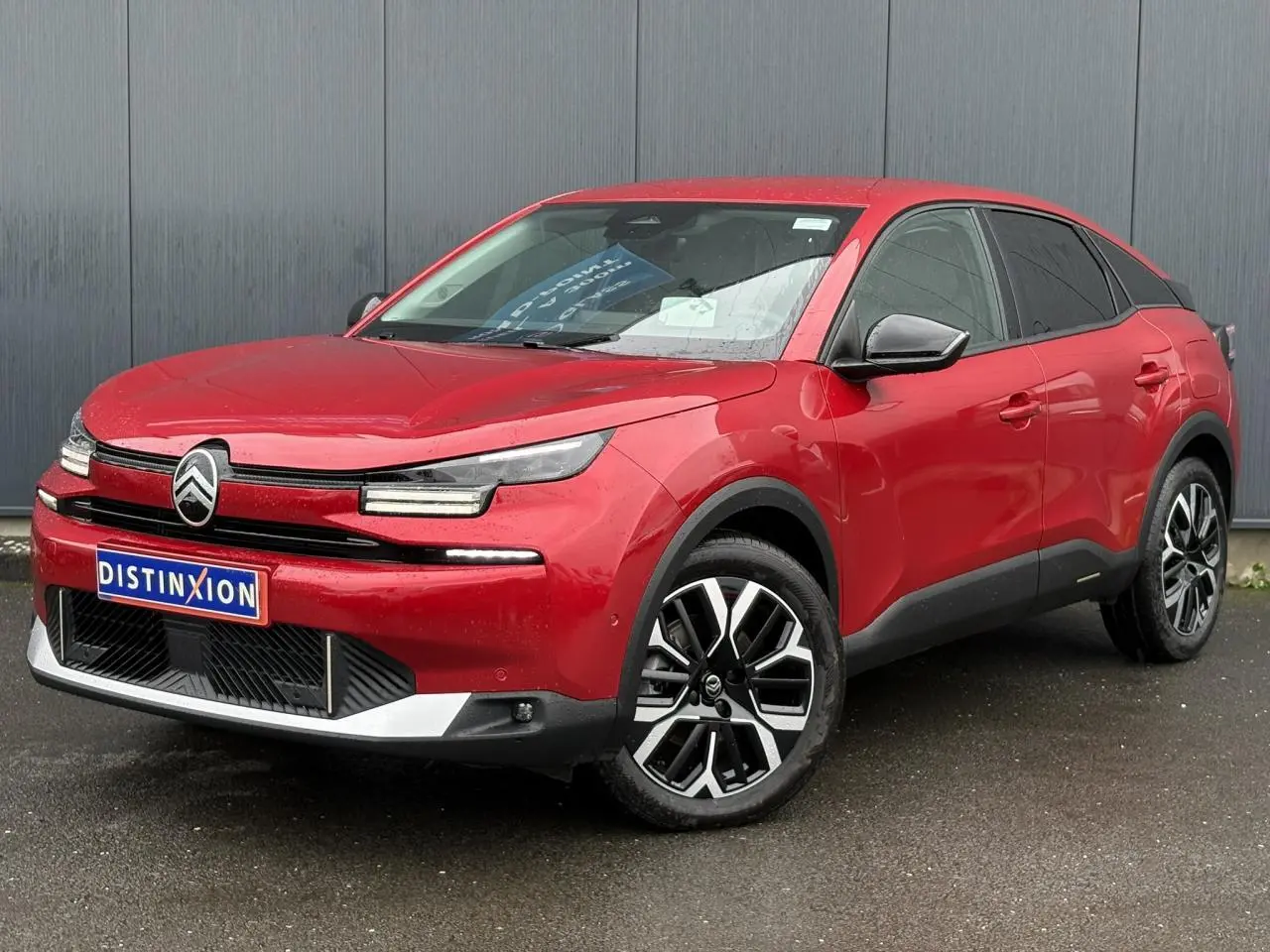 Vue 3/4 avant droite d'une Citroën C4 hybride 2025 Rouge Elixir avec jantes alliage et phares LED distinctifs.