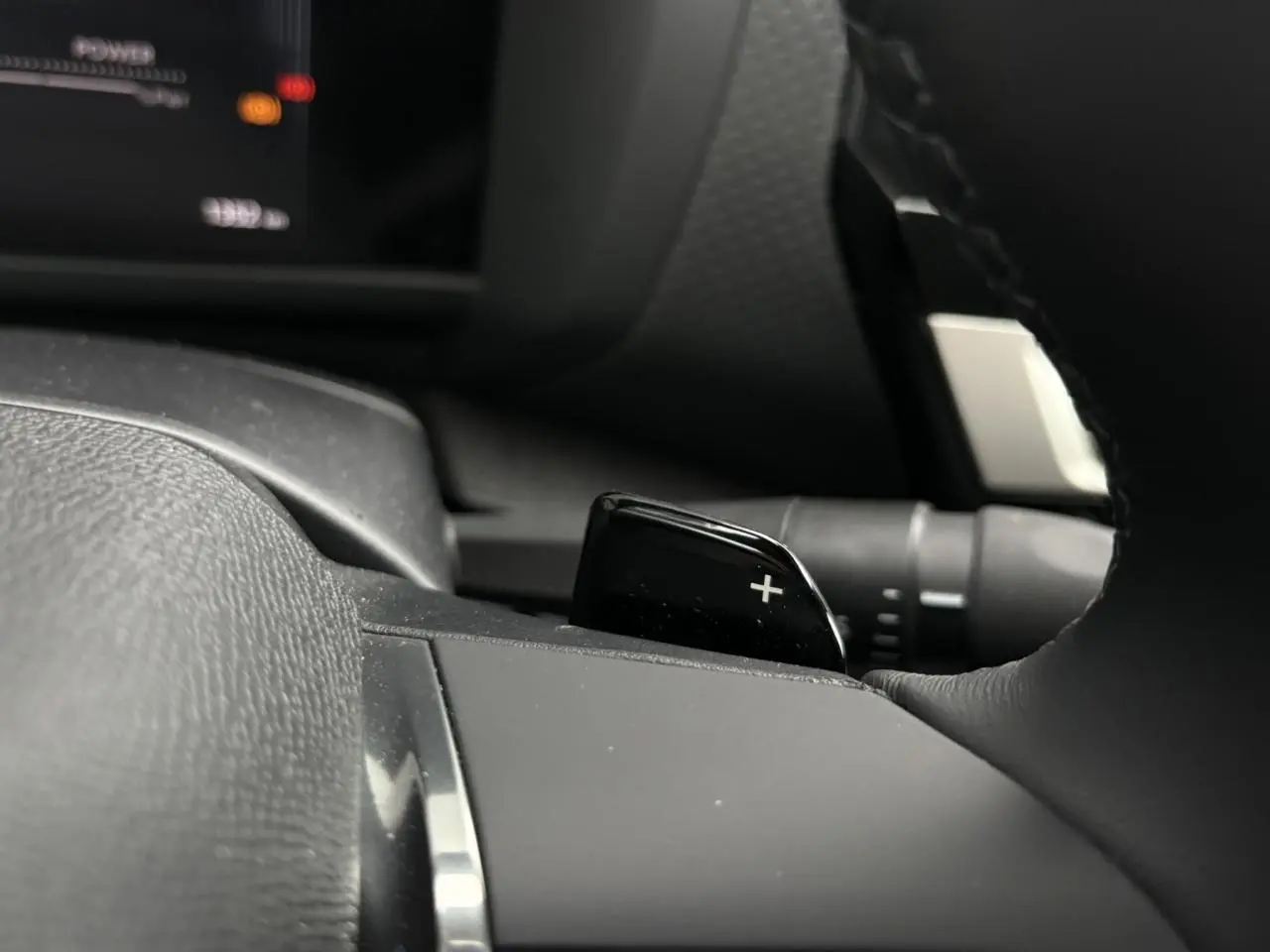 Gros plan sur la palette de changement de rapports "+" côté droit du volant cuir d'une Citroën C4 Hybrid 2025.