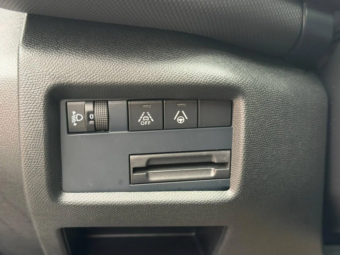 Gros plan sur les commandes de réglage des phares et d'aide à la conduite du tableau de bord du Citroën C5 Aircross noir.