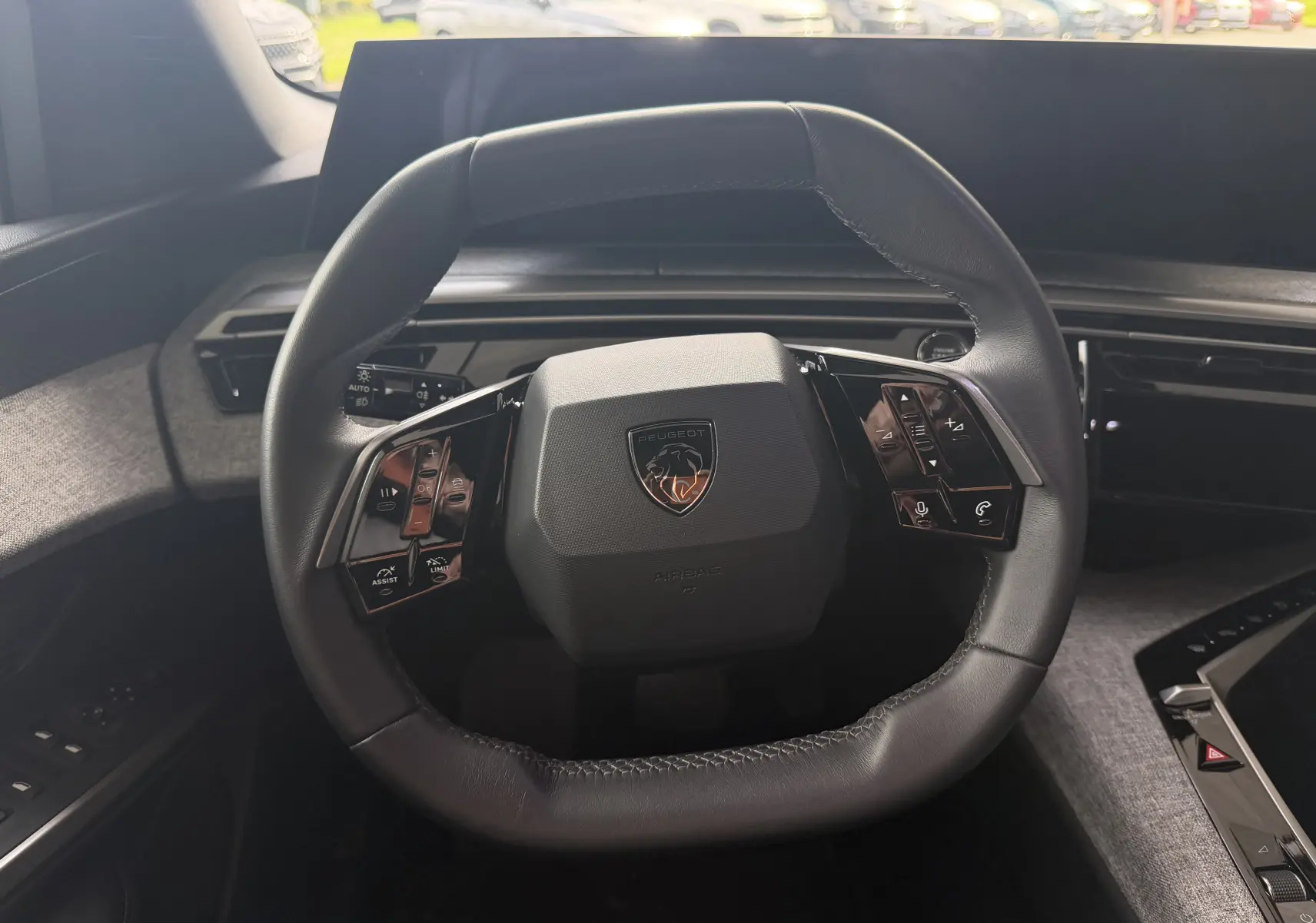 Vue rapprochée du volant cuir noir du Peugeot 1007 Hybrid 145 avec commandes intégrées et logo lion central.