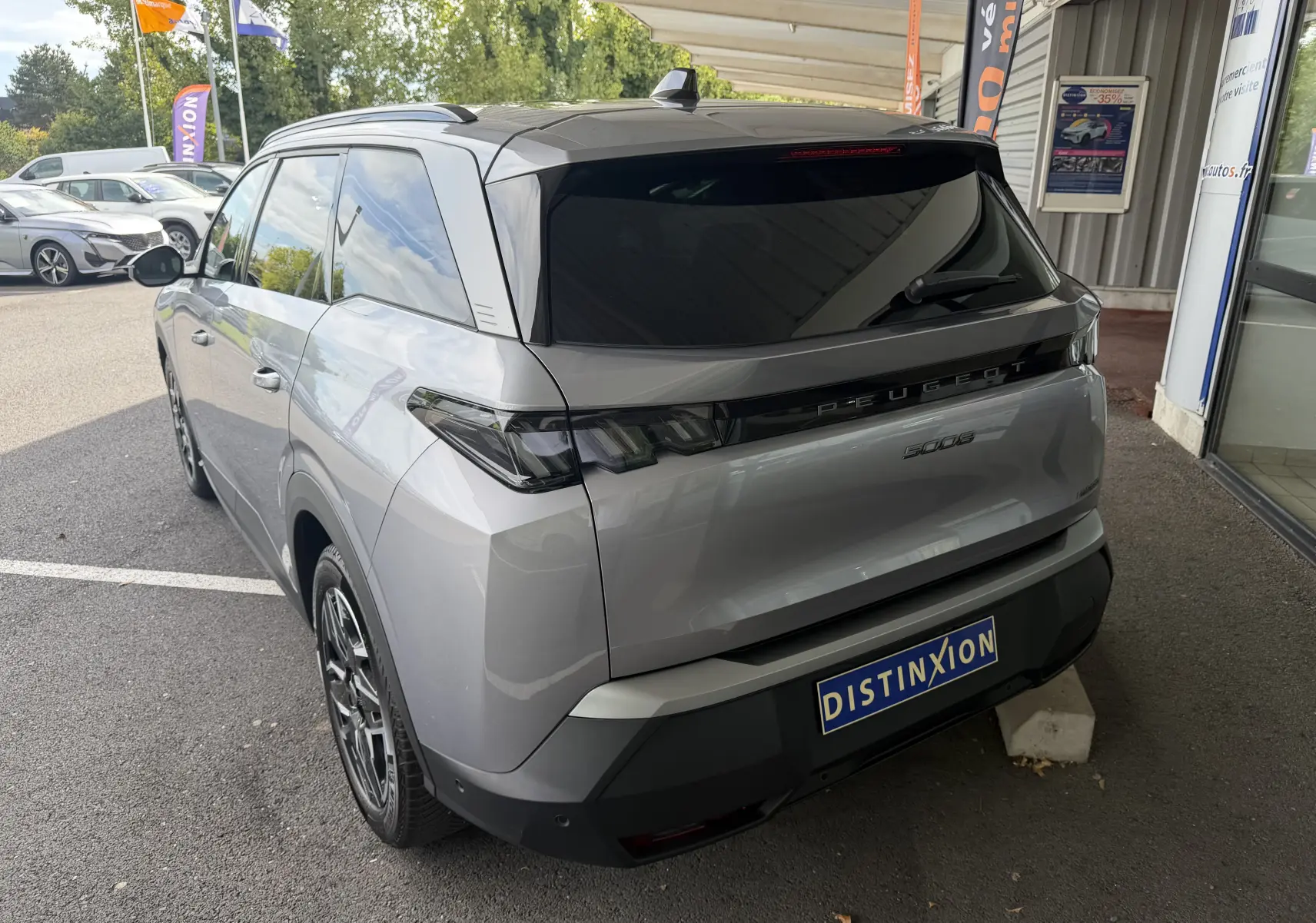 Vue 3/4 arrière droite d’un Peugeot 5008 gris artense avec vitres teintées et jantes alliage noir.