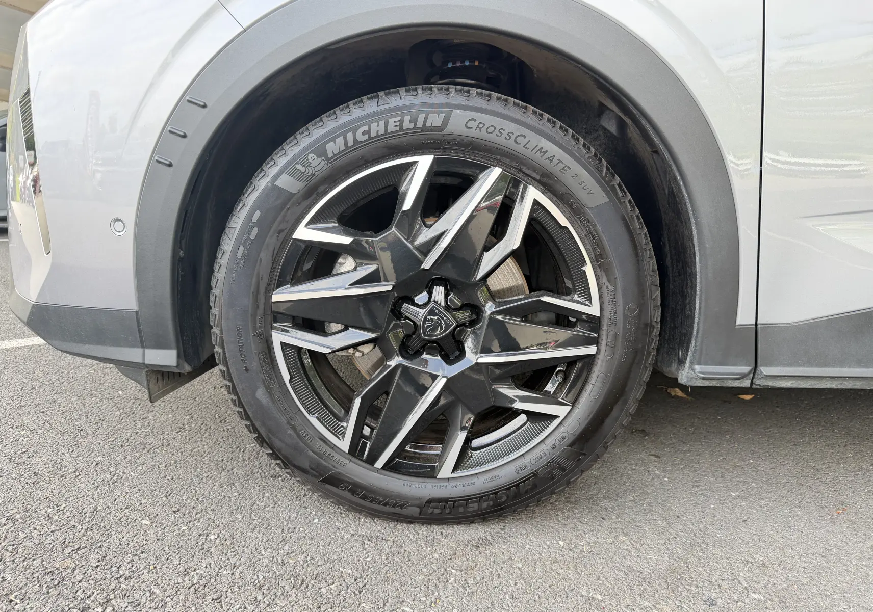 Gros plan sur la roue avant gauche d’un Peugeot 1007 gris Artense avec jante aluminium 19 pouces au design moderne.