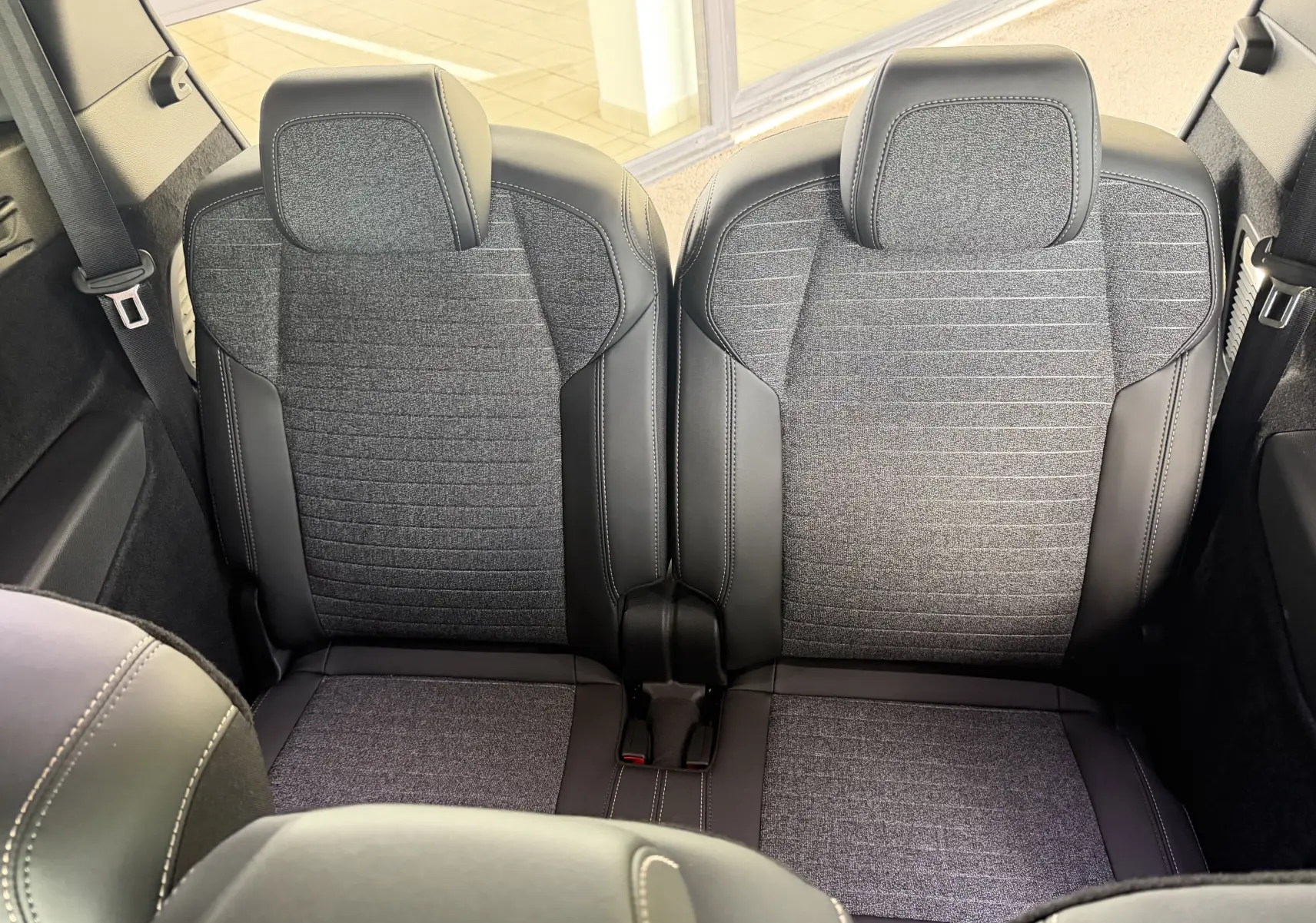 Vue rapprochée des sièges arrière en tissu gris et cuir noir du Peugeot 1007 Hybrid 145, finition Allure 2026.
