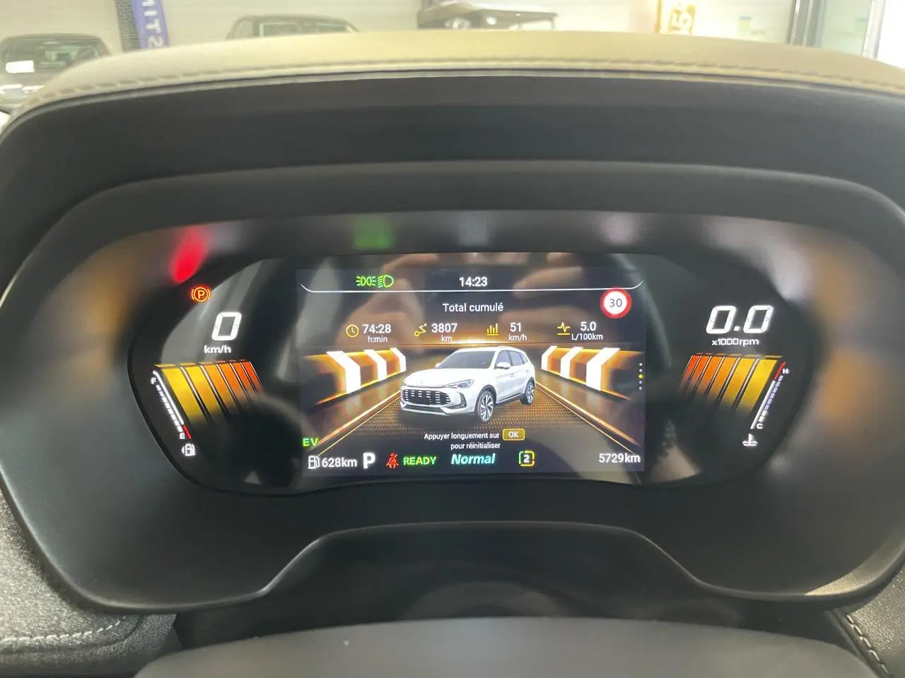 Tableau de bord numérique du MG ZS Hybrid+ 2026 affichant la consommation et une image du véhicule gris clair en vue de face.