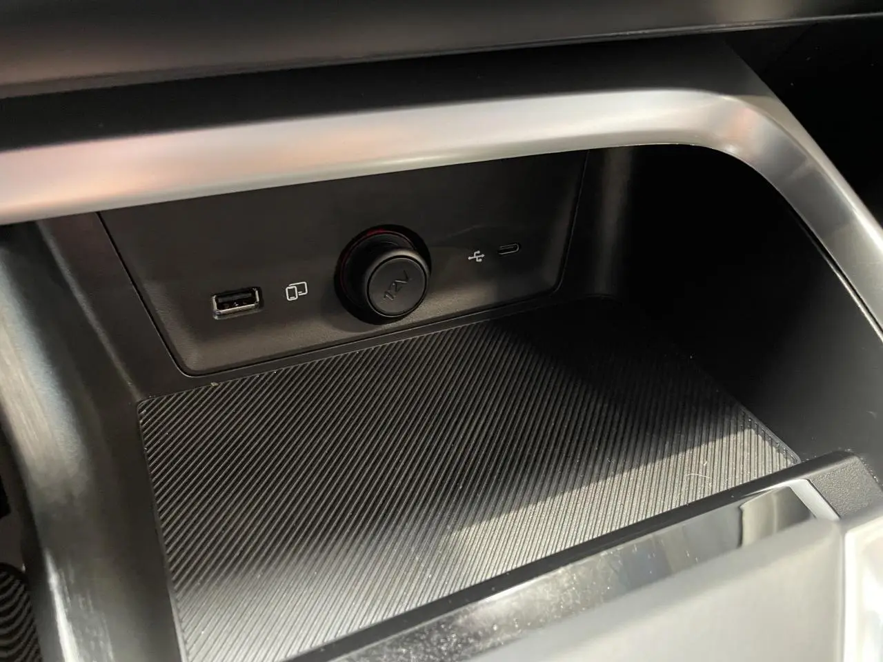 Gros plan sur la console centrale du MG ZS 1.5 Hybrid+ 2026, montrant les prises USB et la prise 12V dans un intérieur noir.